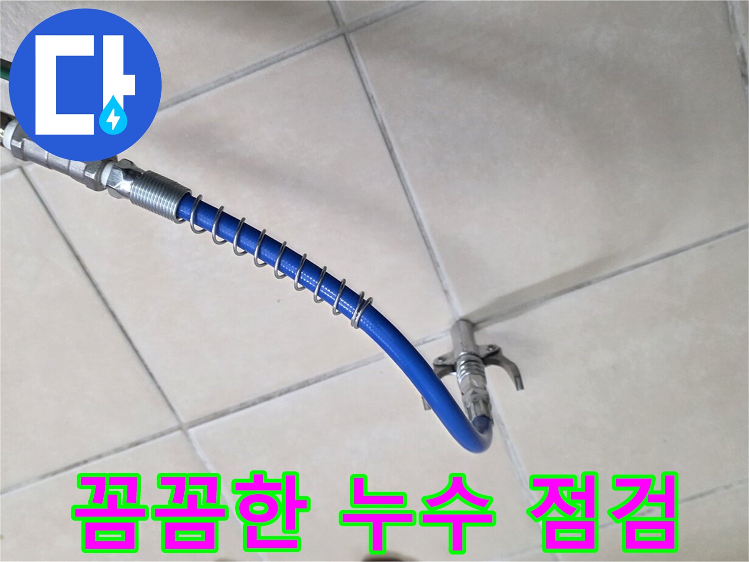 파란색 압력 호스와 금속 커플링이 타일 바닥에 놓여 있는 모습