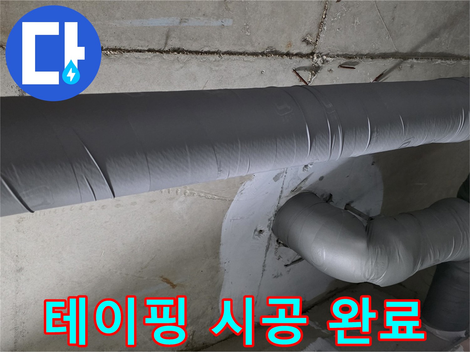 회색 단열재로 덮여 있는 천장 내부의 굴곡진 배관 구조입니다.