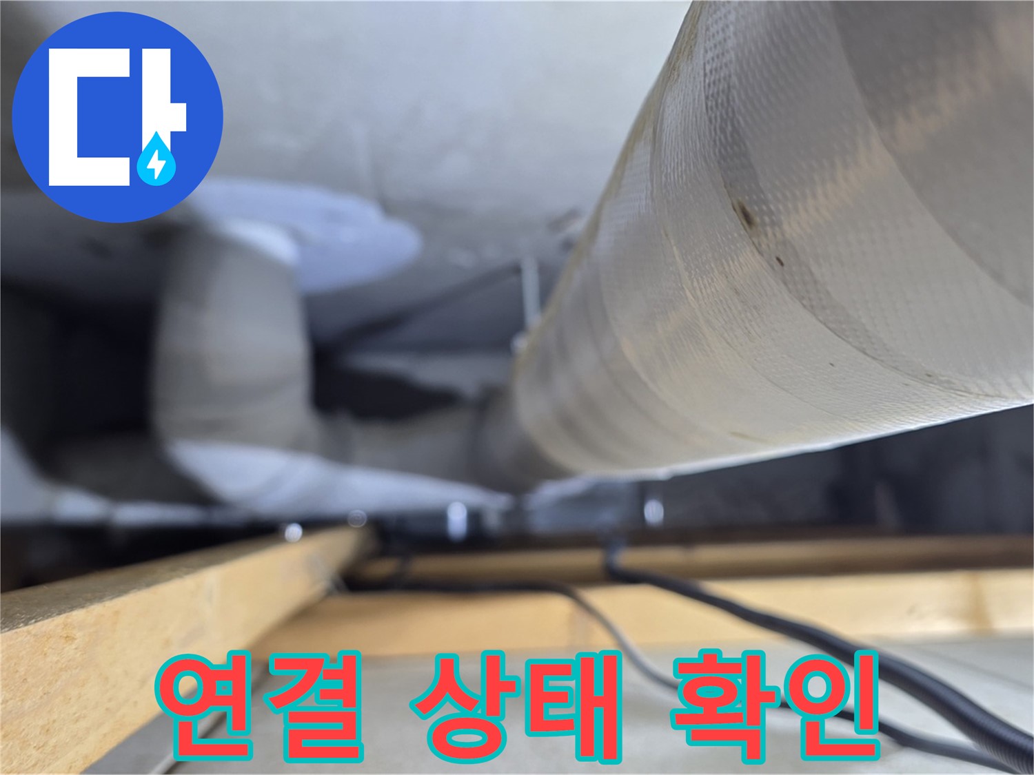 아파트 천장 내부의 주름진 배수 호스와 수평으로 지나가는 배관의 연결 상태를 보여줍니다.