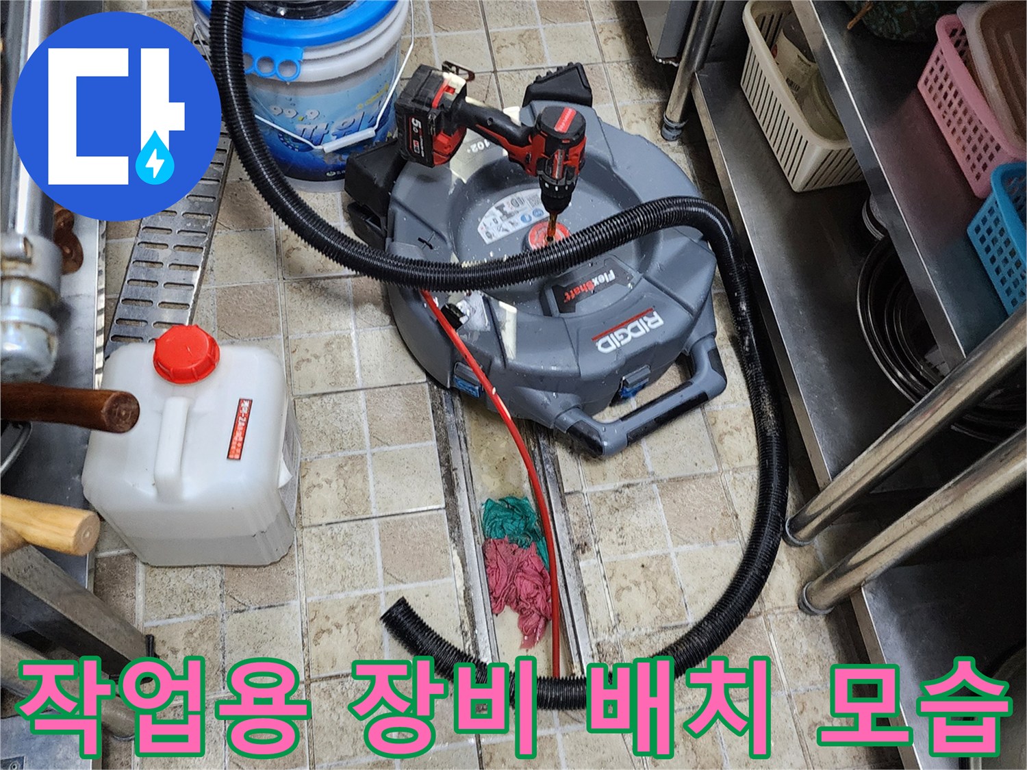바닥 타일 위에 놓인 산업용 청소기와 전기 드릴 세트