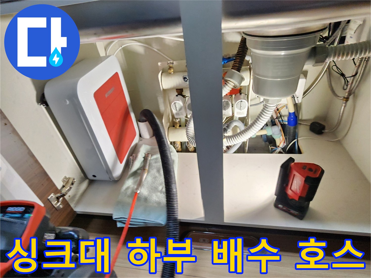 싱크대 아래쪽 굵은 주름관과 급수 라인의 복잡한 연결 구조