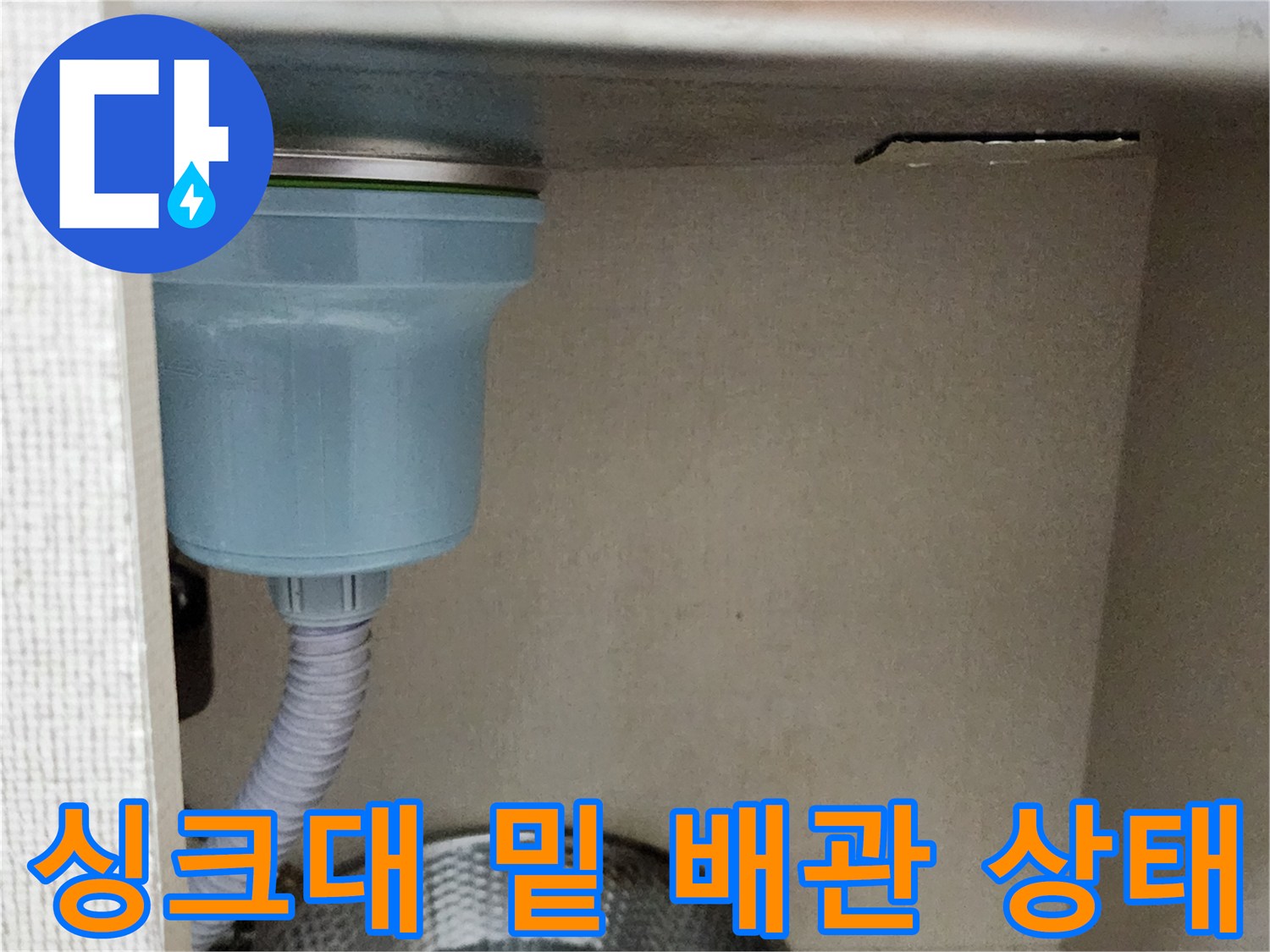 싱크대 아래쪽 회색 주름관과 스테인리스 대야의 모습입니다.