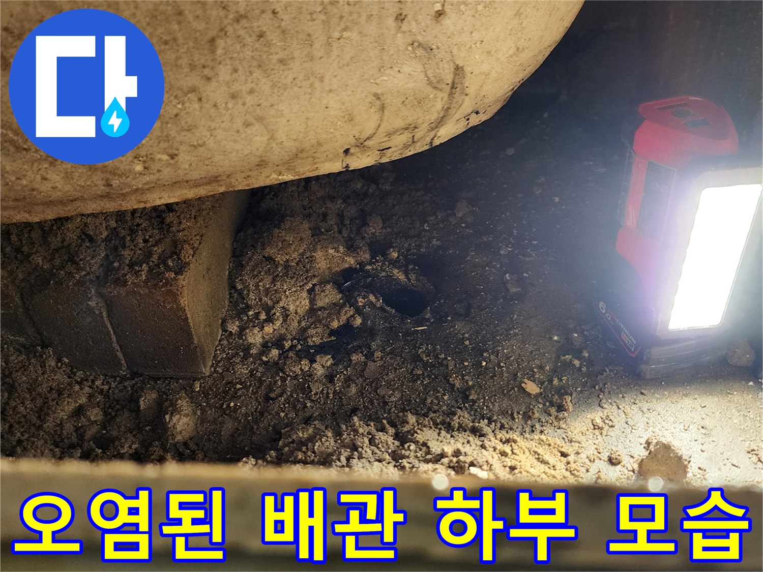 손전등으로 비춘-배관 주변의 이물질과 젖은 바닥면