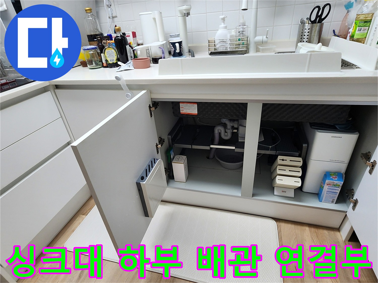 싱크대 아래쪽 하부장 내부의 배수 호스와 분배기 노출 사진