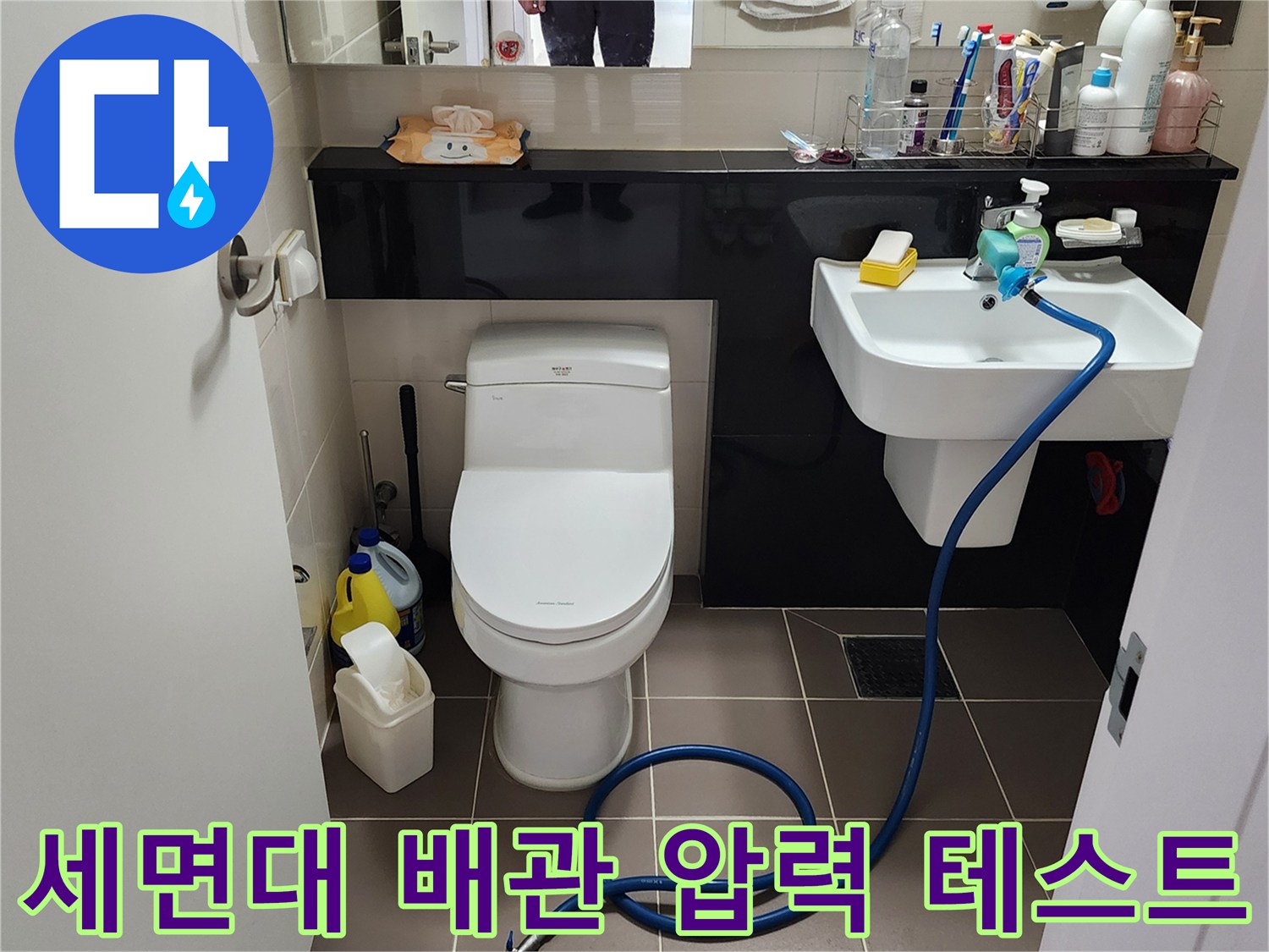 화장실 세면대 아래쪽 수전에 연결된 누수 탐지용 호스와 작업 중인 모습