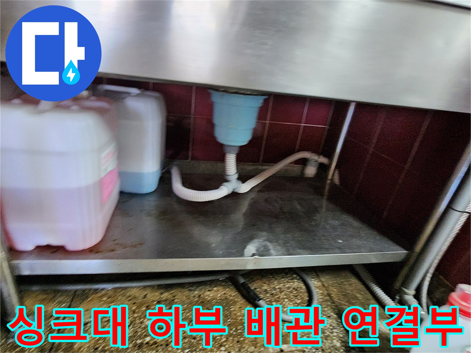 싱크대 밑 화이트 배수 호스와 파란색 배수구 부속 모습