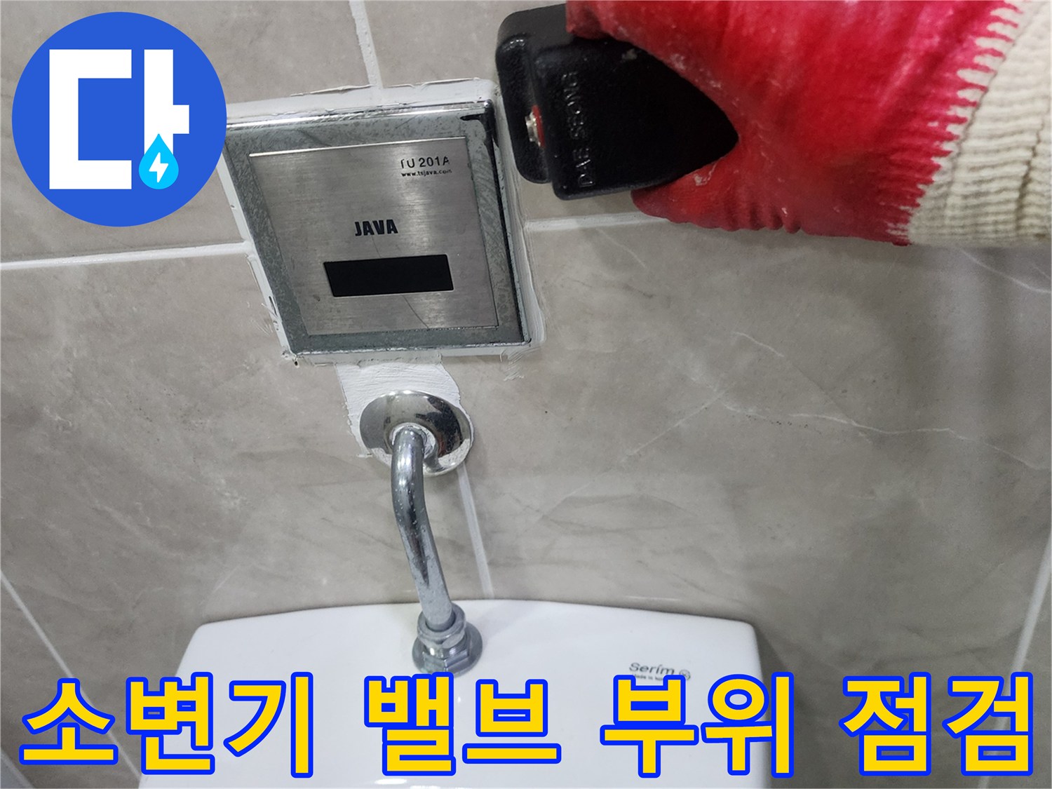 소변기 상단에 위치한 자동 세척 밸브와 연결 배관을 확인하는 사진입니다.