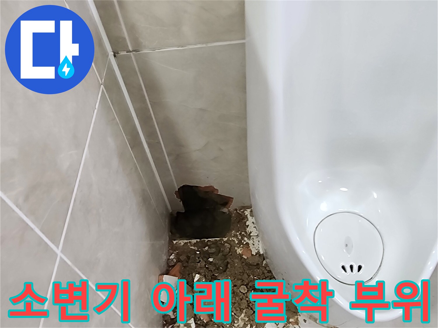 소변기 하단 벽면 타일을 제거하여 노출된 배관 주변 상태를 보여주는 사진입니다.