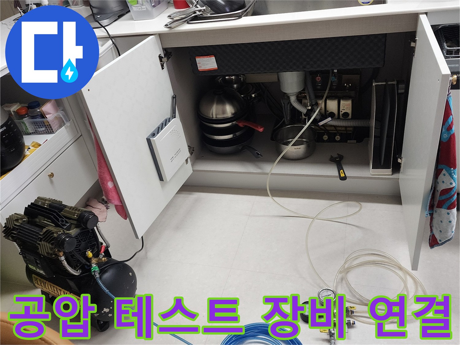 누수 진단용 공압 장비-싱크대 배관에 호스를 연결하여 압력을 주입하는 모습입니다.