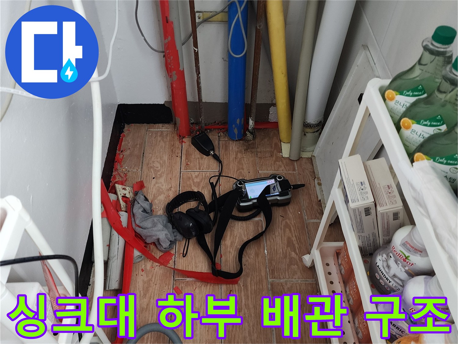 싱크대 아래 복잡한 배관들과 탐지 장비가 놓인 현장 사진