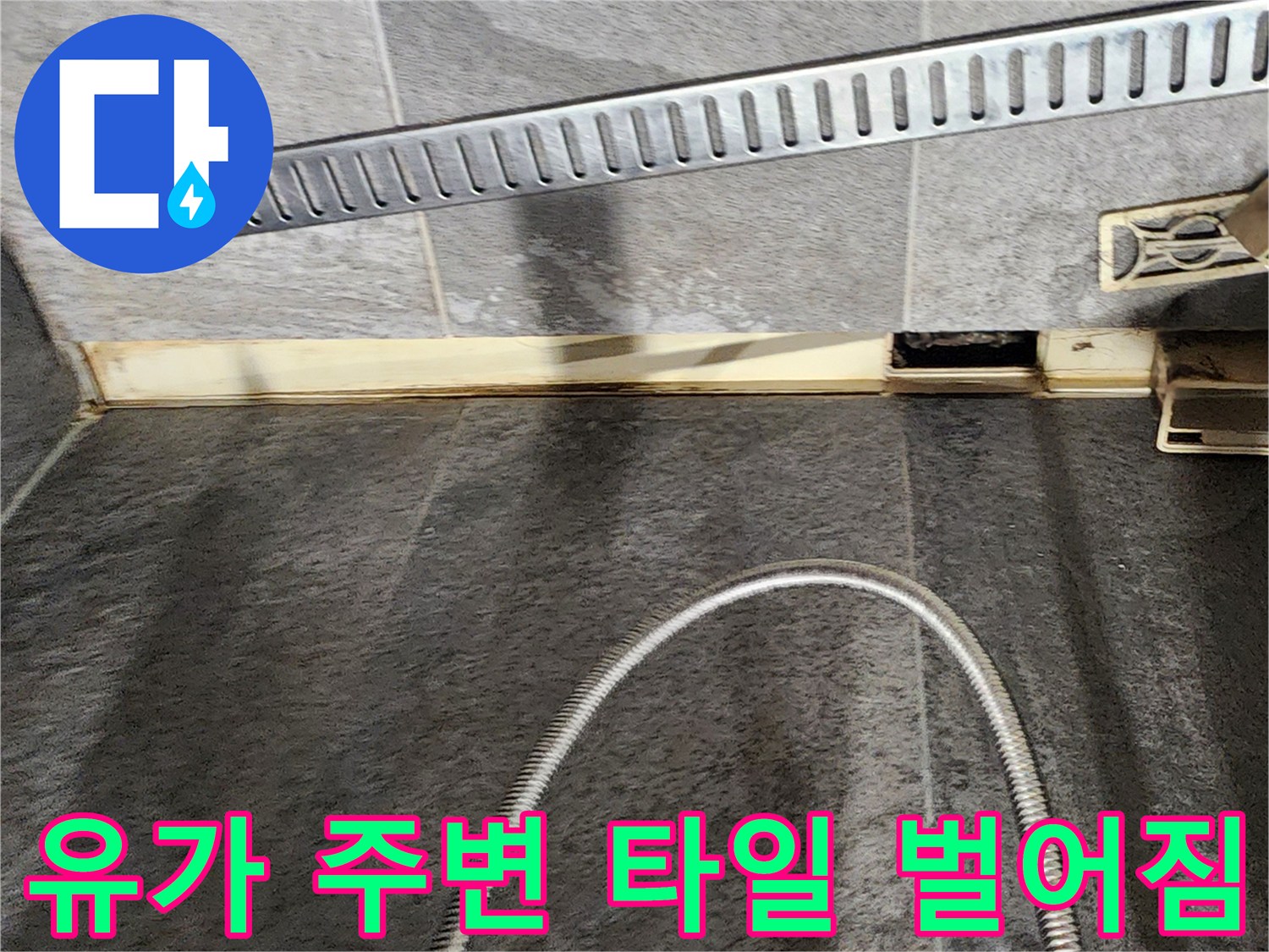 욕실 배수구 유가와 바닥 타일 사이의 균열 부위를 촬영한 사진입니다.