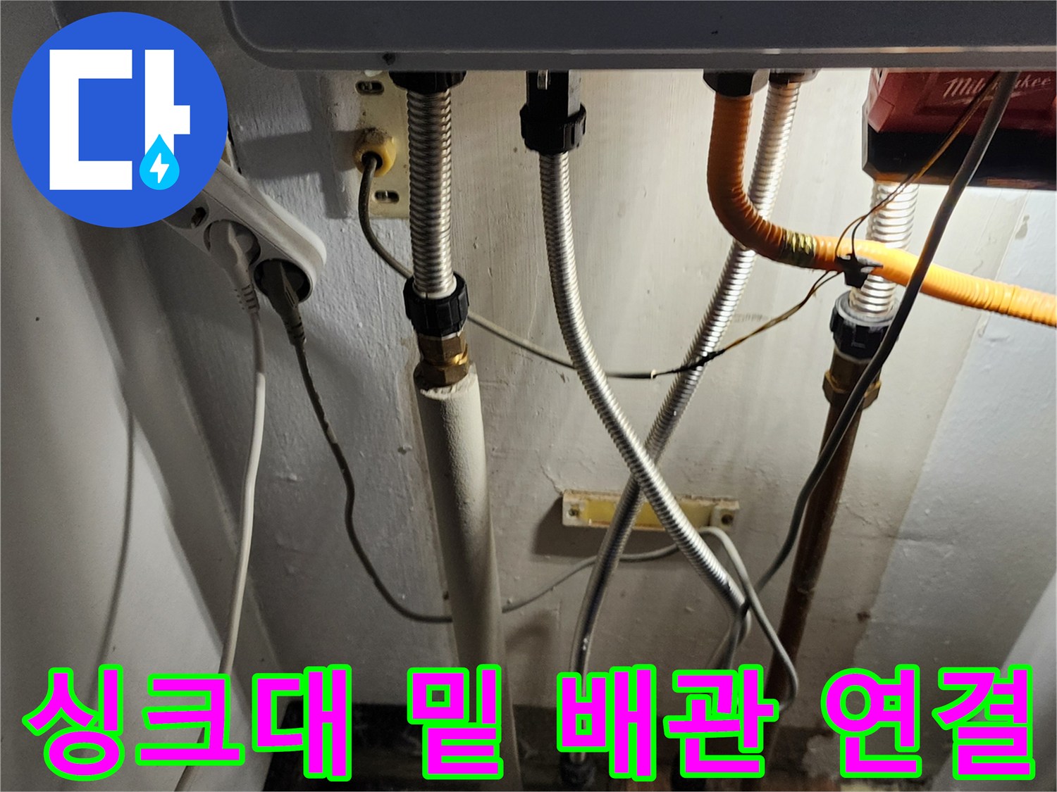 주방 하부 배관의 은색 주름관과 노란 호스 부위 상세 사진