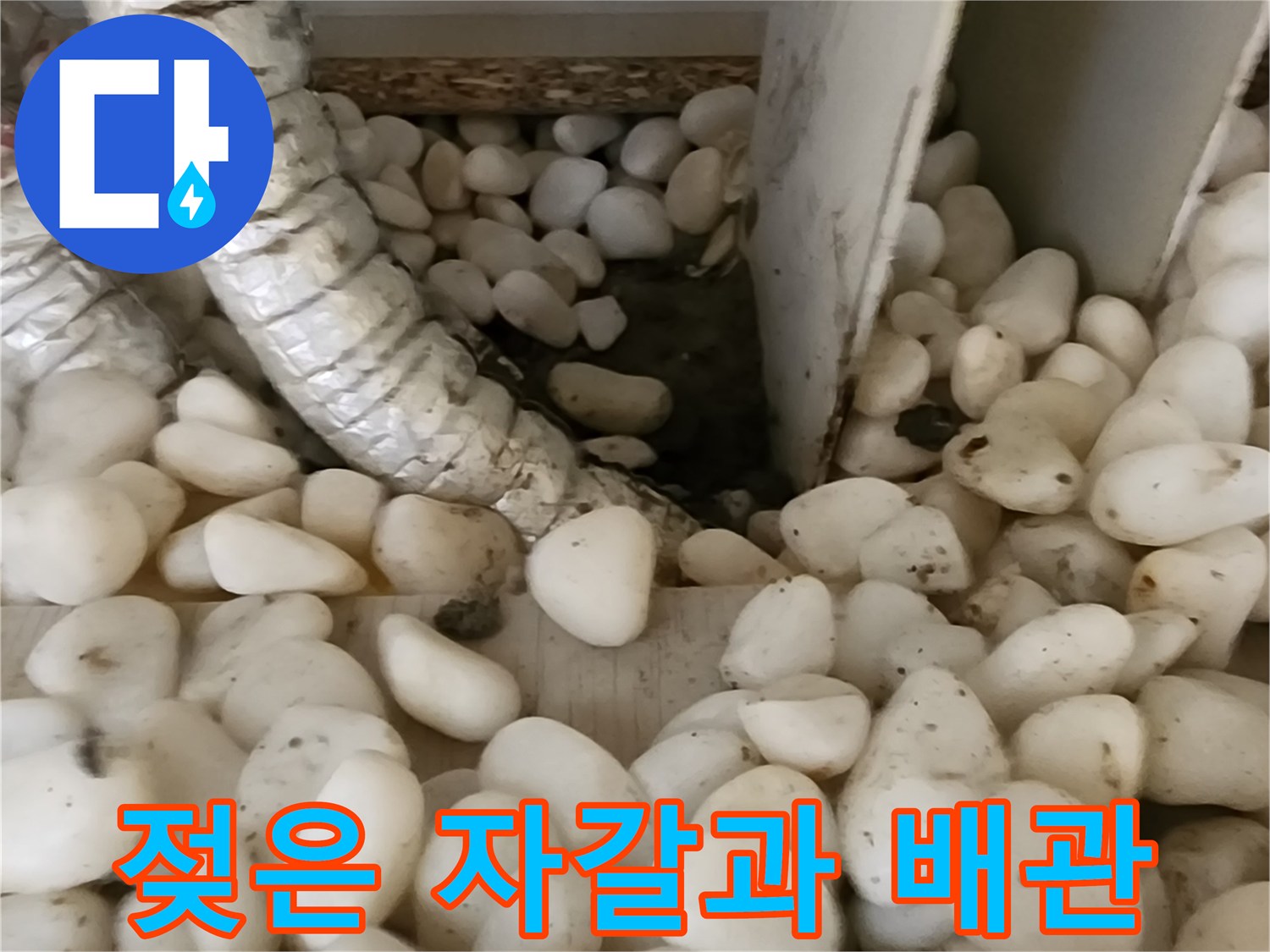 보온재로 감싸진 배관 사이의 젖은 자갈