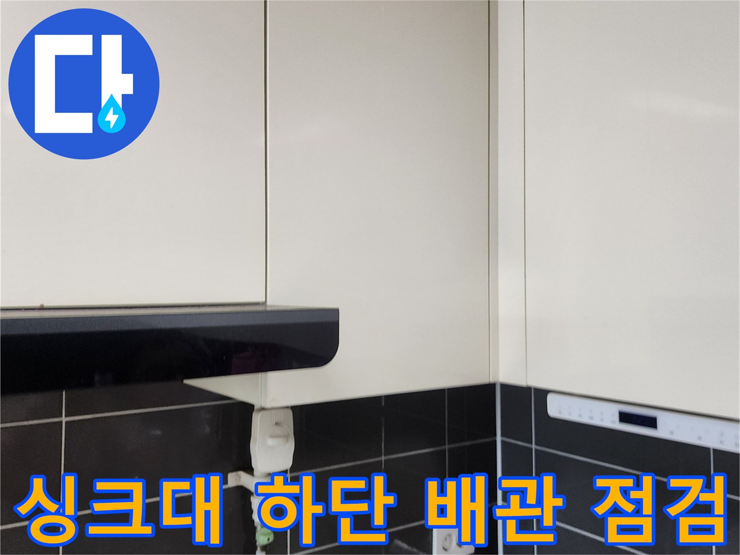주방 싱크대 하부장 내부의 배관과 전기 콘센트 사진