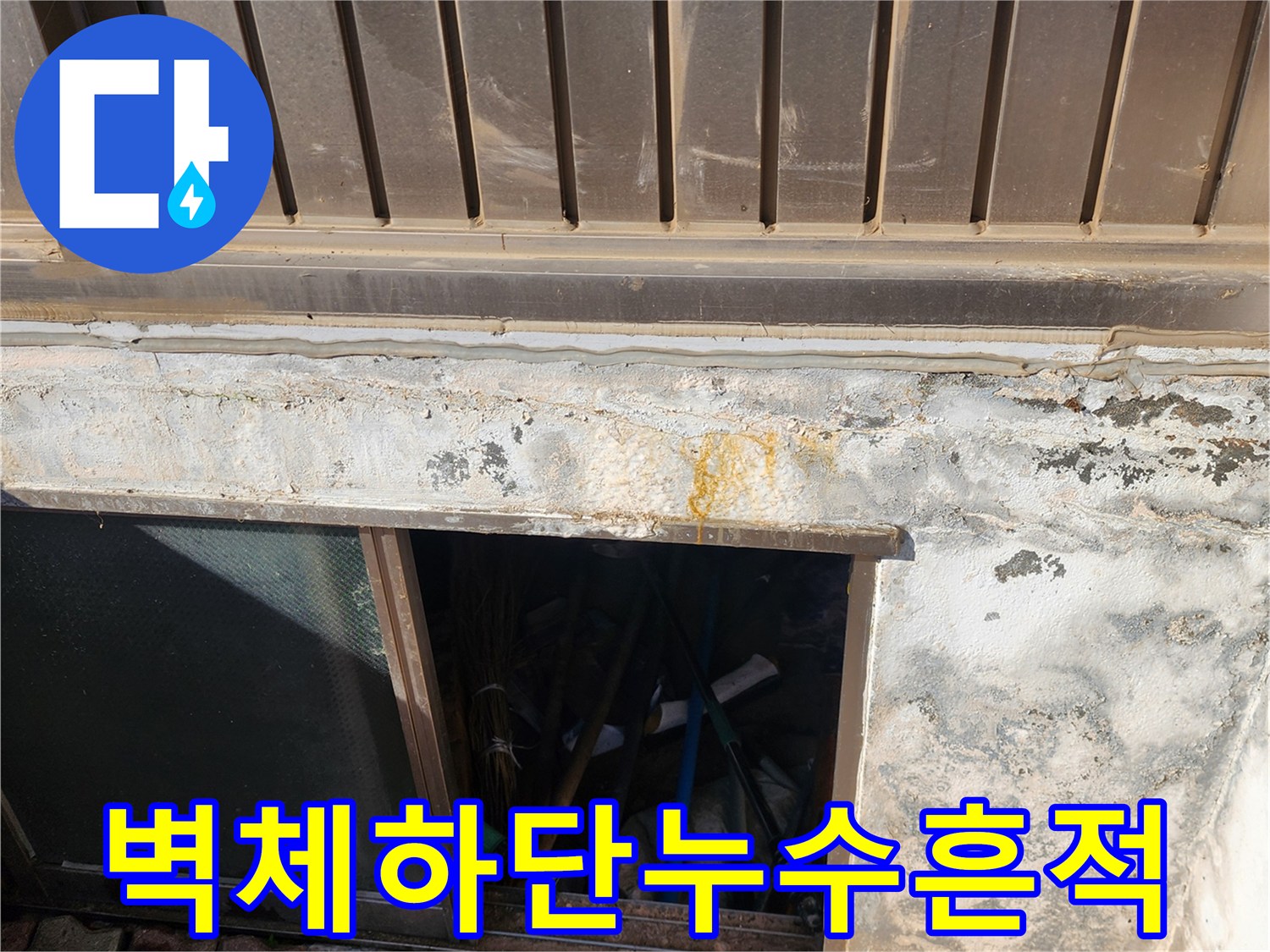 금속 패널 하단 콘크리트 면에 나타난 누수 흔적과 황색 얼룩