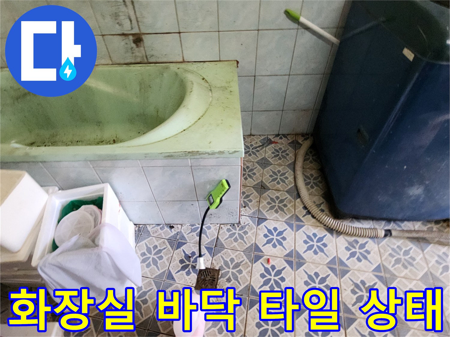 욕실 바닥의 푸른색 패턴 타일과 욕조 주변 배관 연결 부위 근처 모습
