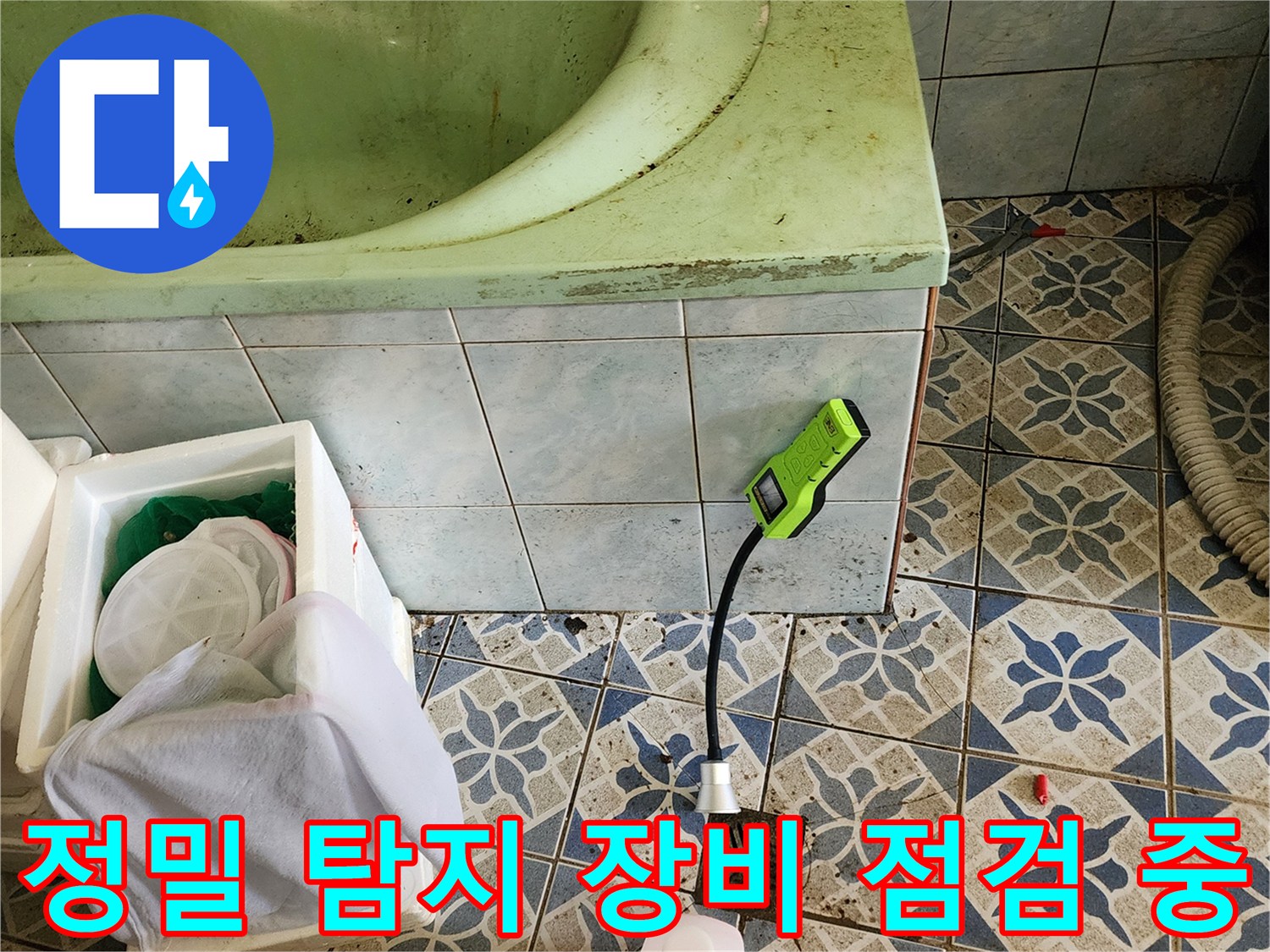 초록색 가스 탐지기가 놓인 욕실 바닥 작업 현장 사진
