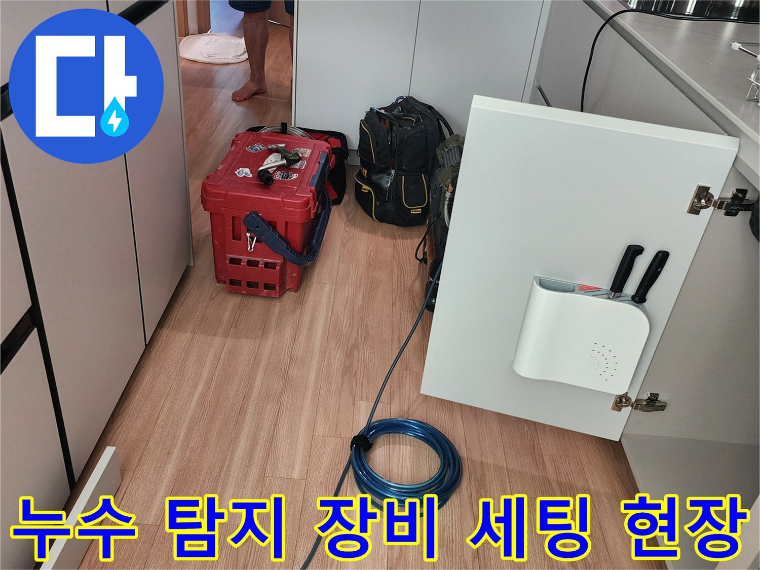 싱크대 하단 배관 점검을 위해 전문 공구와 호스를 배치한 모습입니다.