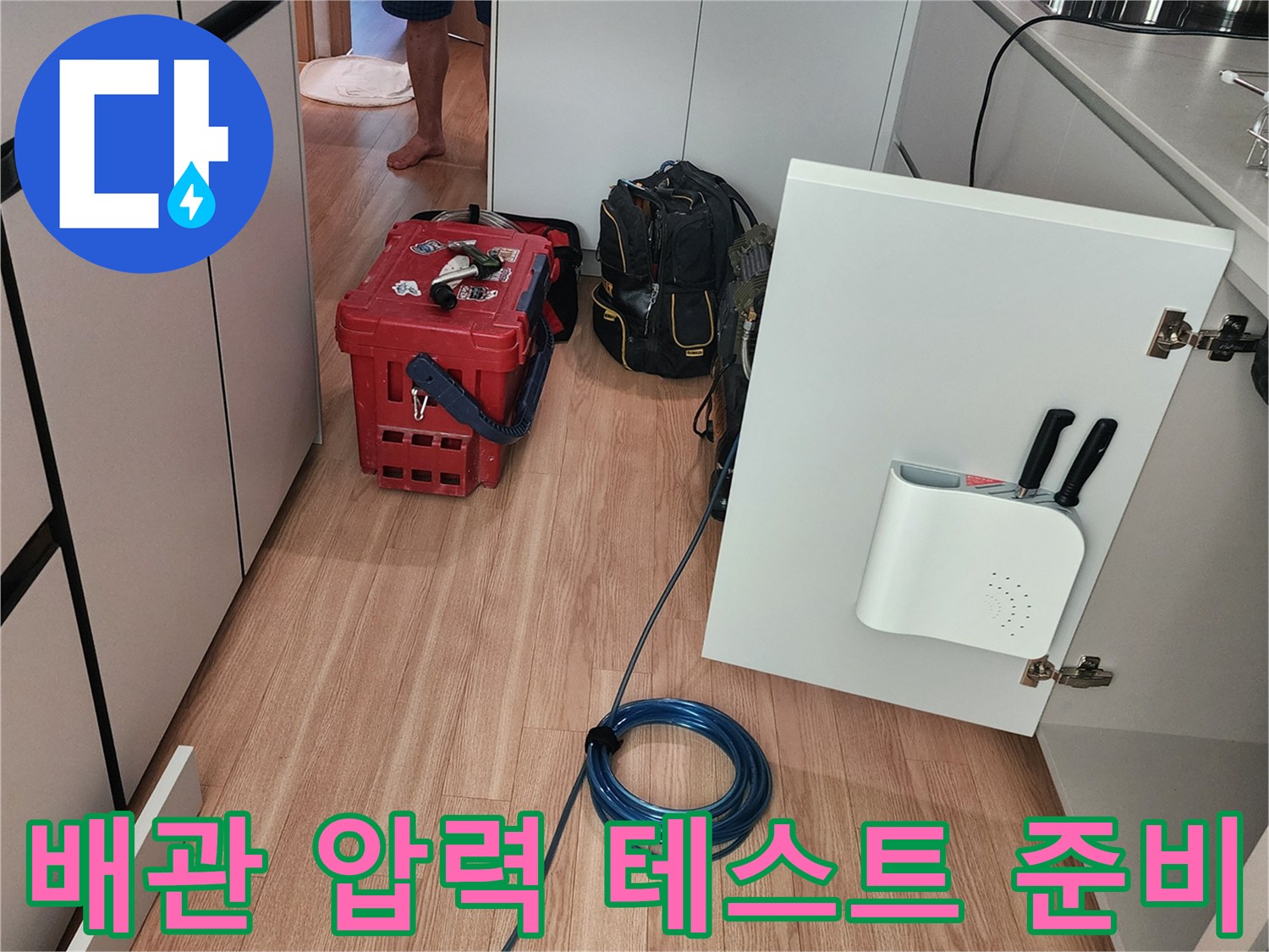싱크대 하부장 근처에 배치된 누수 탐지용 장비와 호스