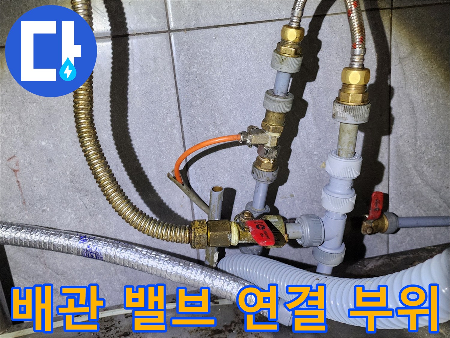 빨간색 밸브와 금속 호스가 연결된 주방 배관 상세 모습