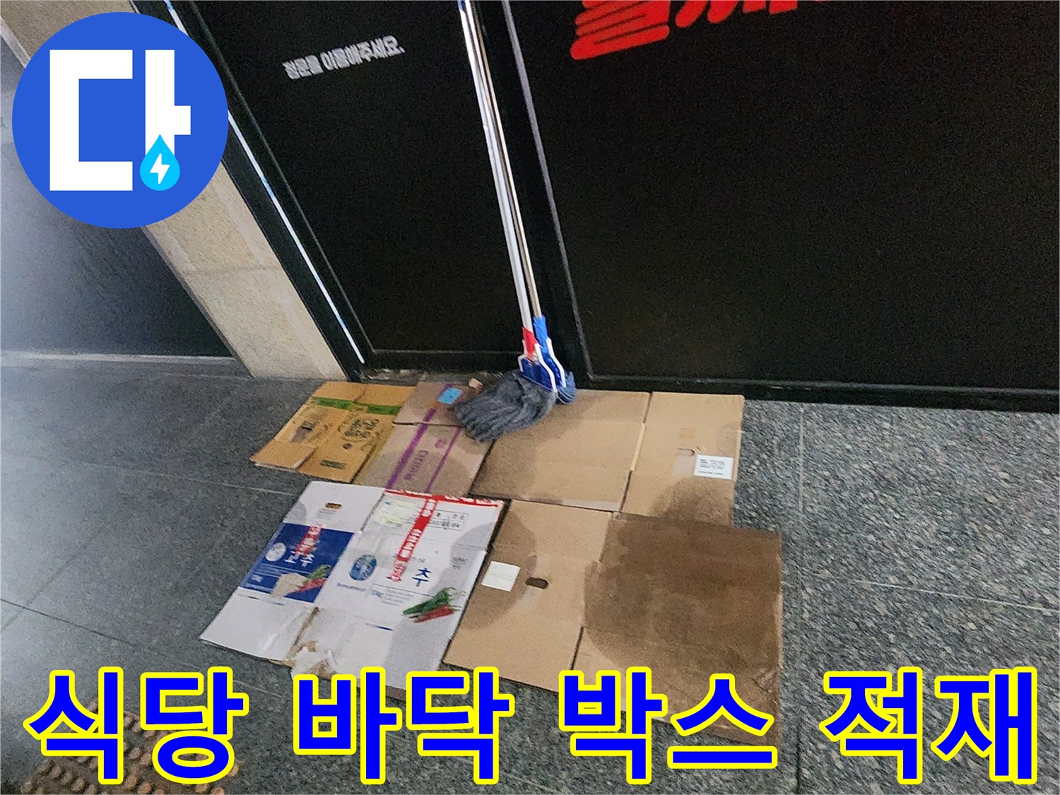 음식점 입구 근처-바닥에 놓인 종이 상자와 청소 도구