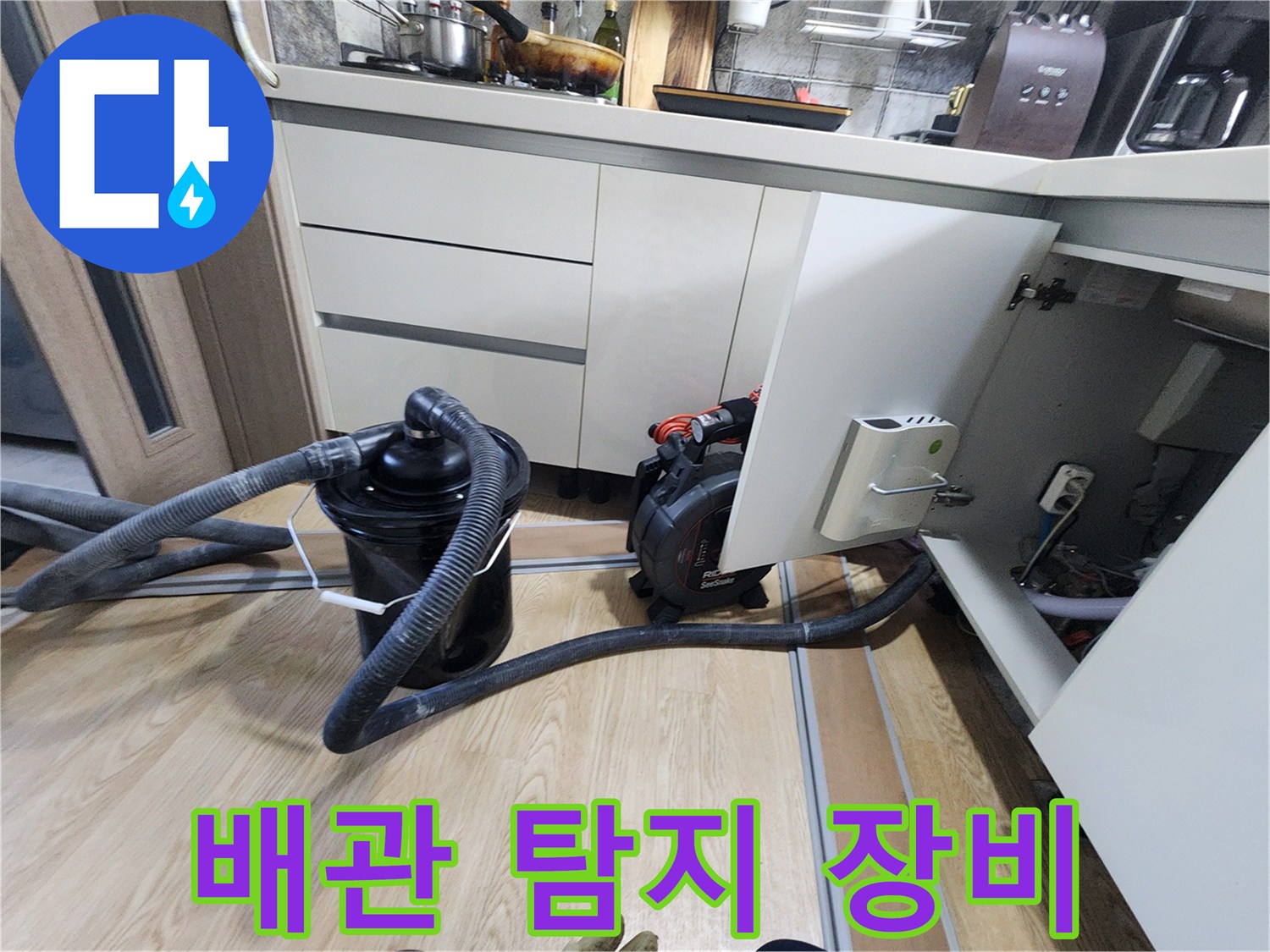 주방 하부 공간에서 배관 내부를 살피기 위해 설치된 전문 탐지 장비와 호스