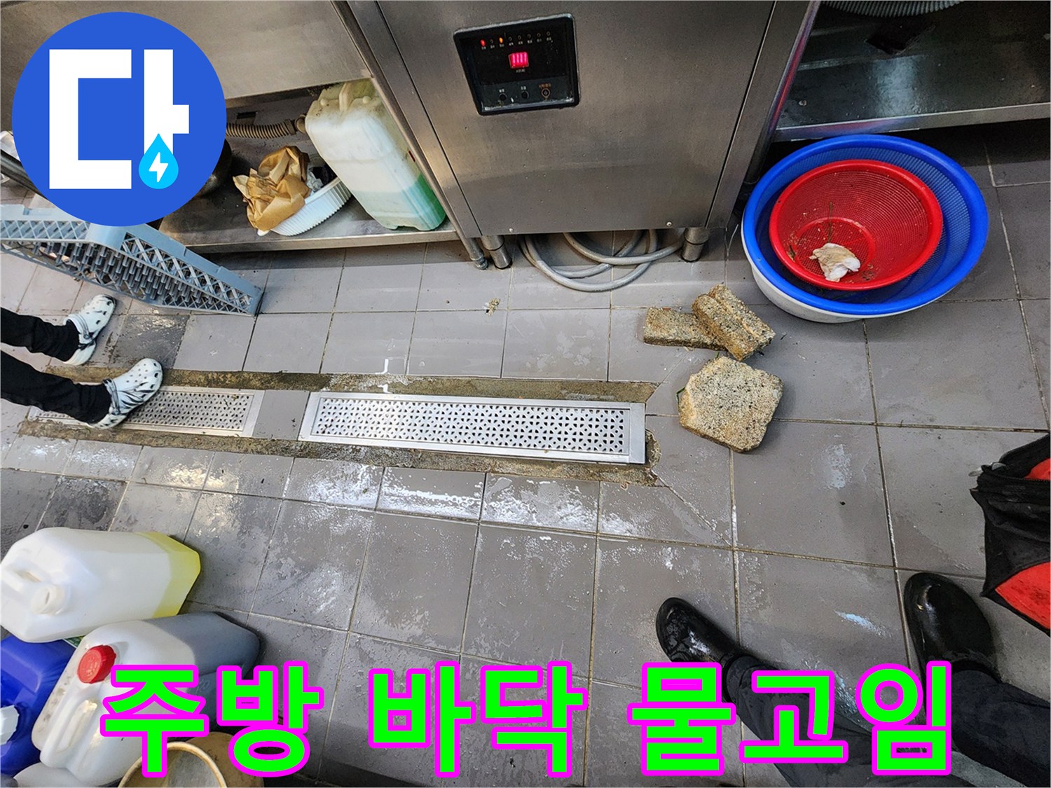 주방 기구 아래 배수 트렌치에 고여 있는 물과 젖은 타일
