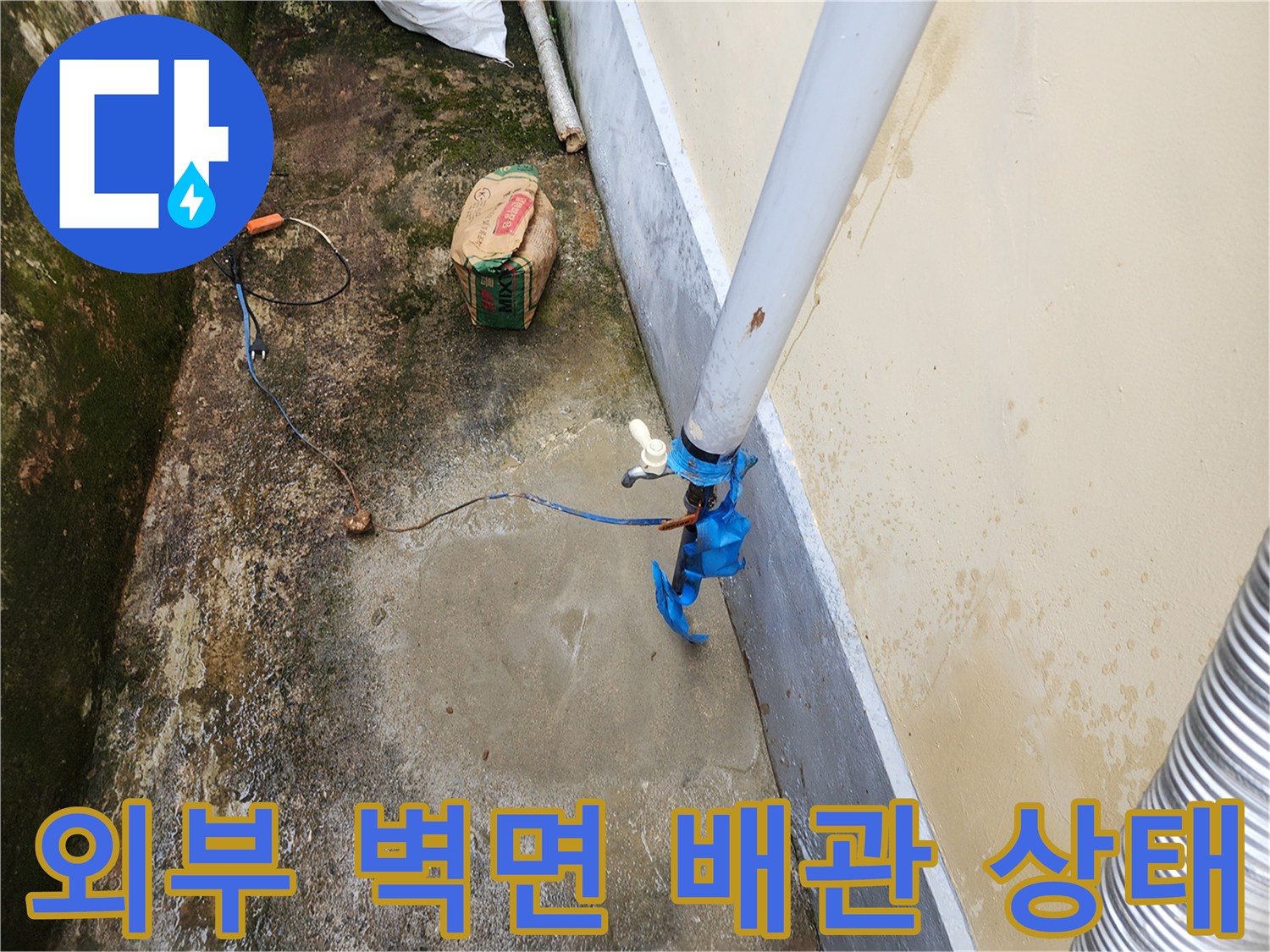 건물 외벽에 설치된 흰색 배관과 젖은 콘크리트 바닥