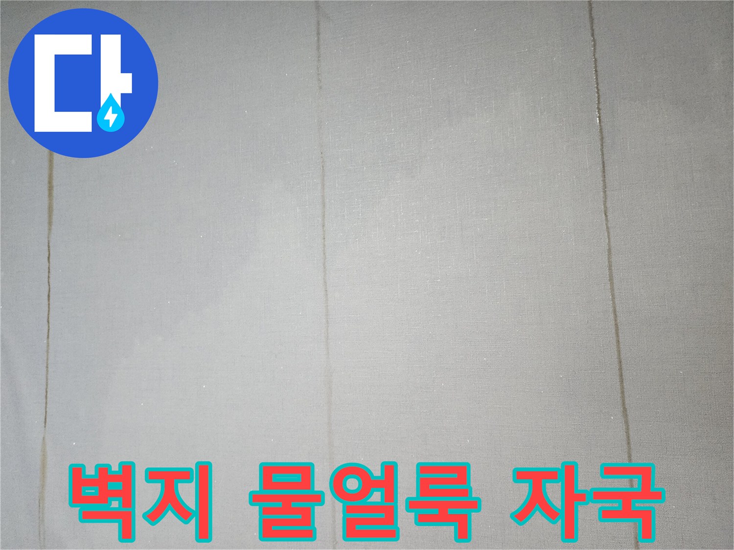 벽지에 발생한 세로 형태의 물자국과 습기로 인한 변색 상태를 보여주는 사진입니다.