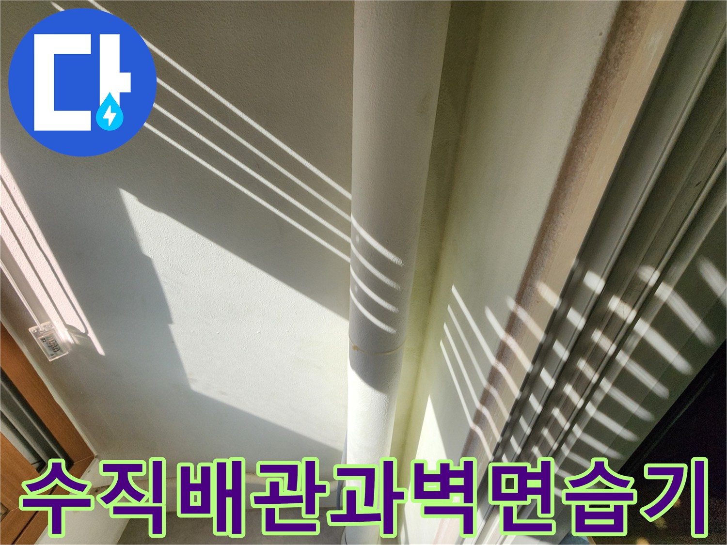 하얀색 수직 배관 주변의 젖은 벽면 상태를 보여주는 사진입니다.