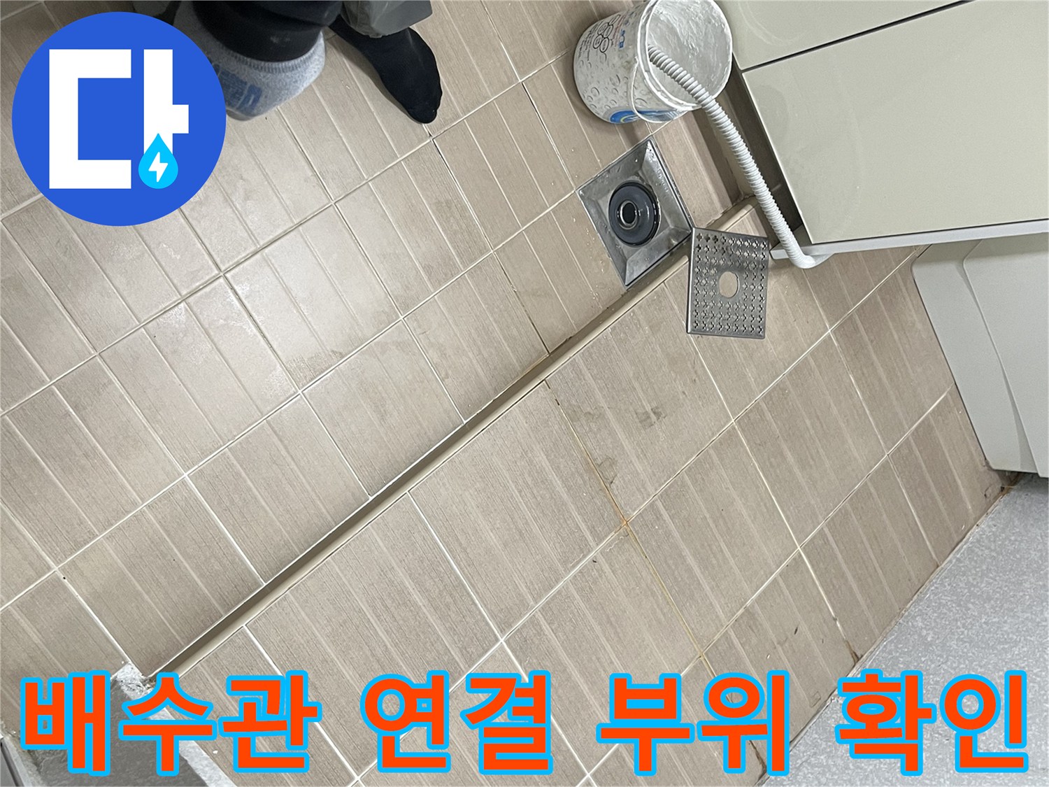 베란다 바닥 배수 트랩과 은색 배수 호스 연결부 상세 사진