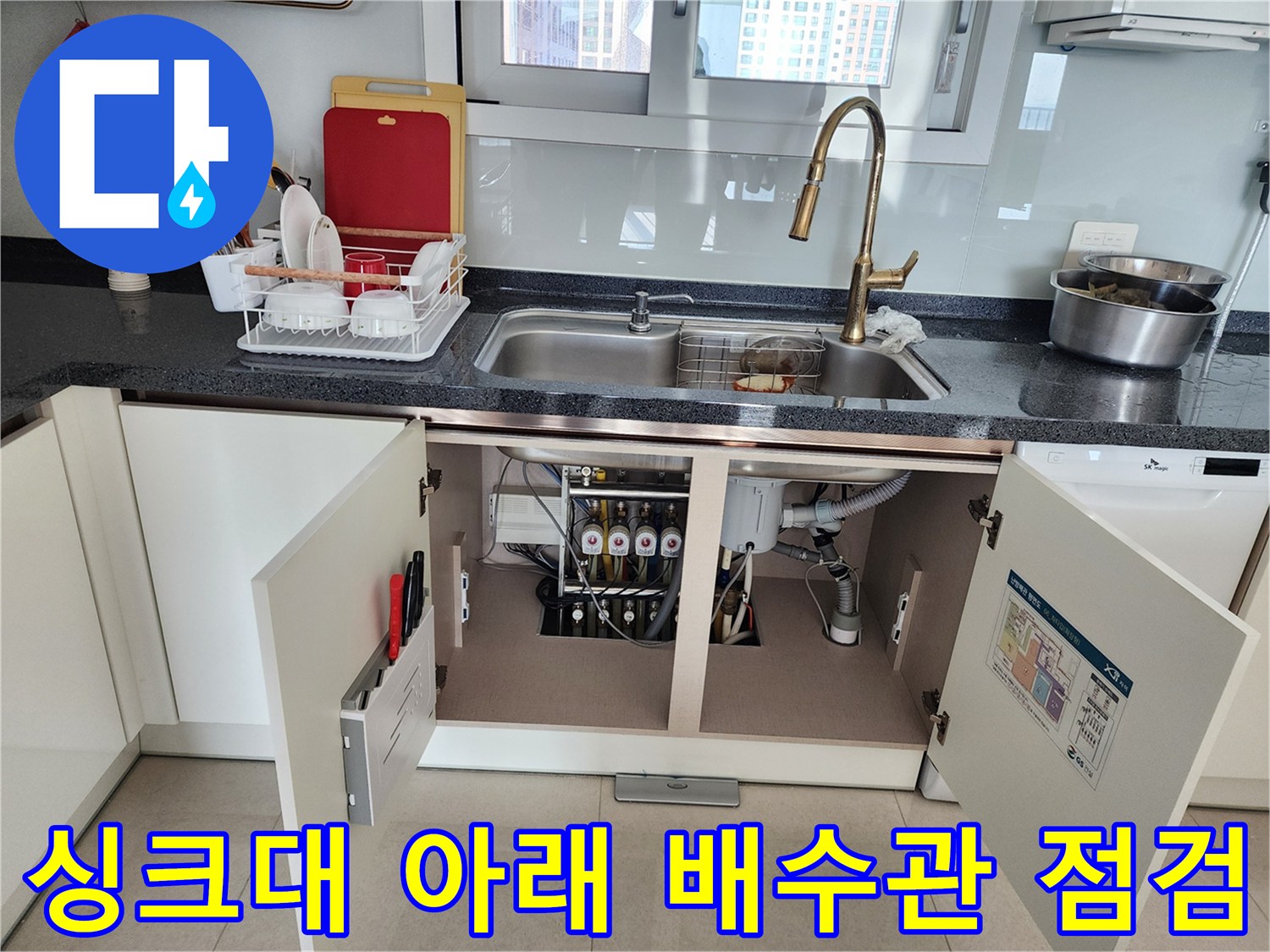 열려 있는 싱크대 하부장 안의 배수관 및 유가 연결 부위 사진