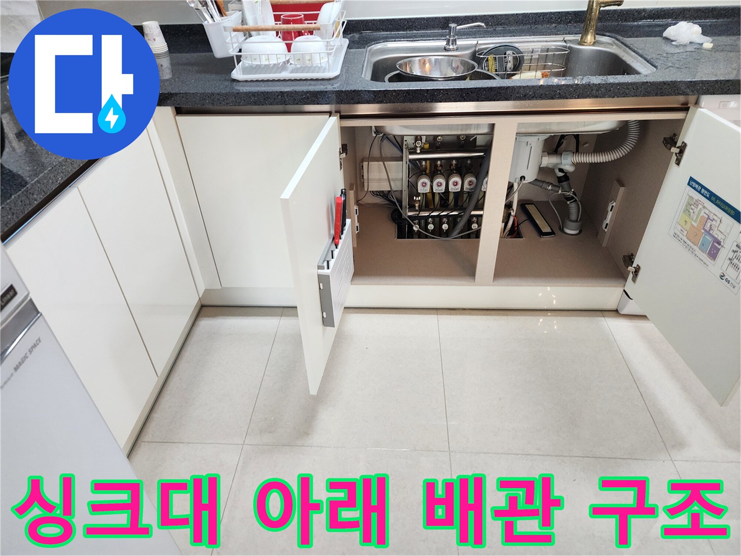 열린 싱크대 수납장 내부의 하수 배수관 및 연결 호스들