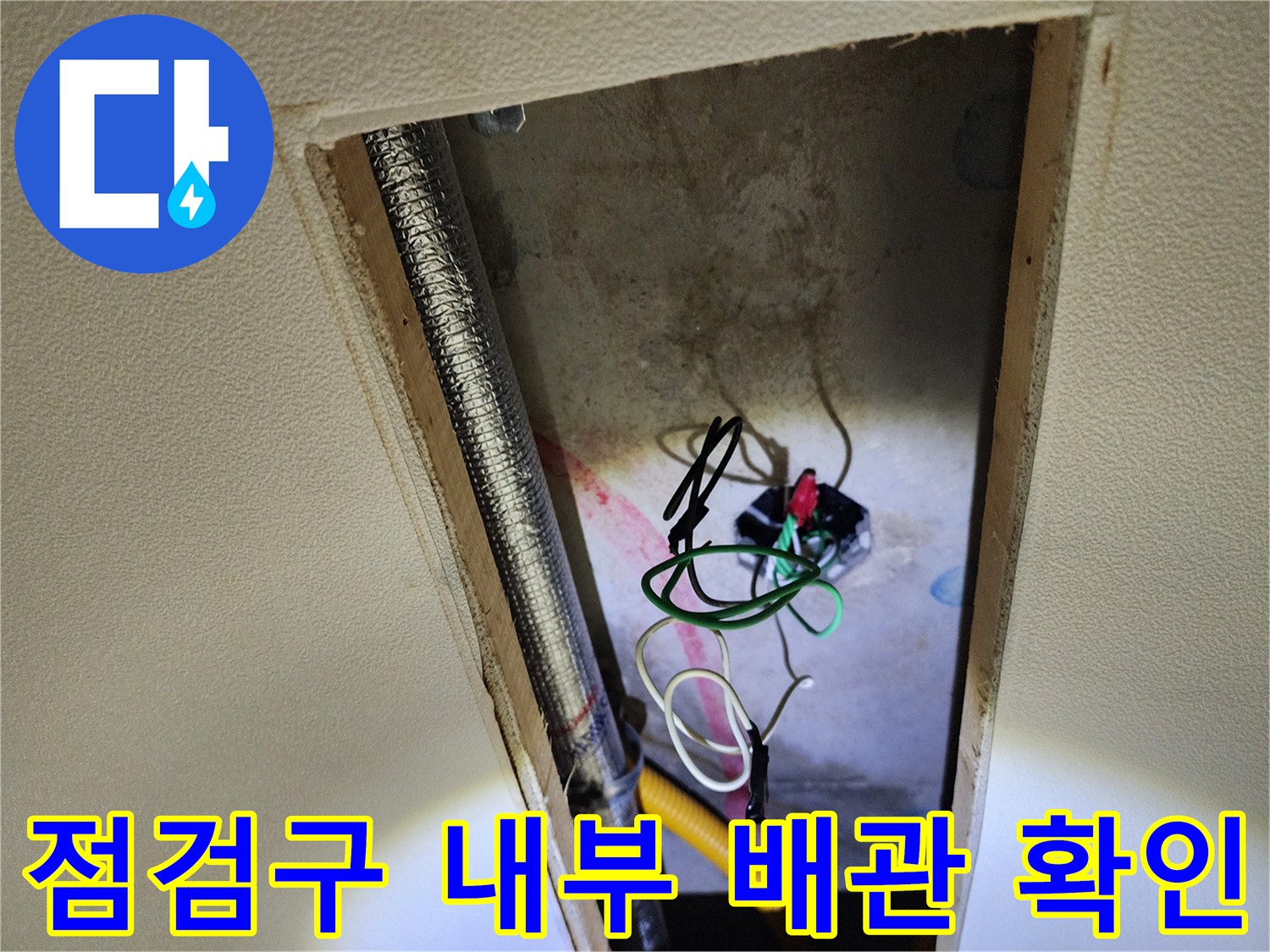 천장 점검구 안쪽의 노출된 배관과 전선 뭉치