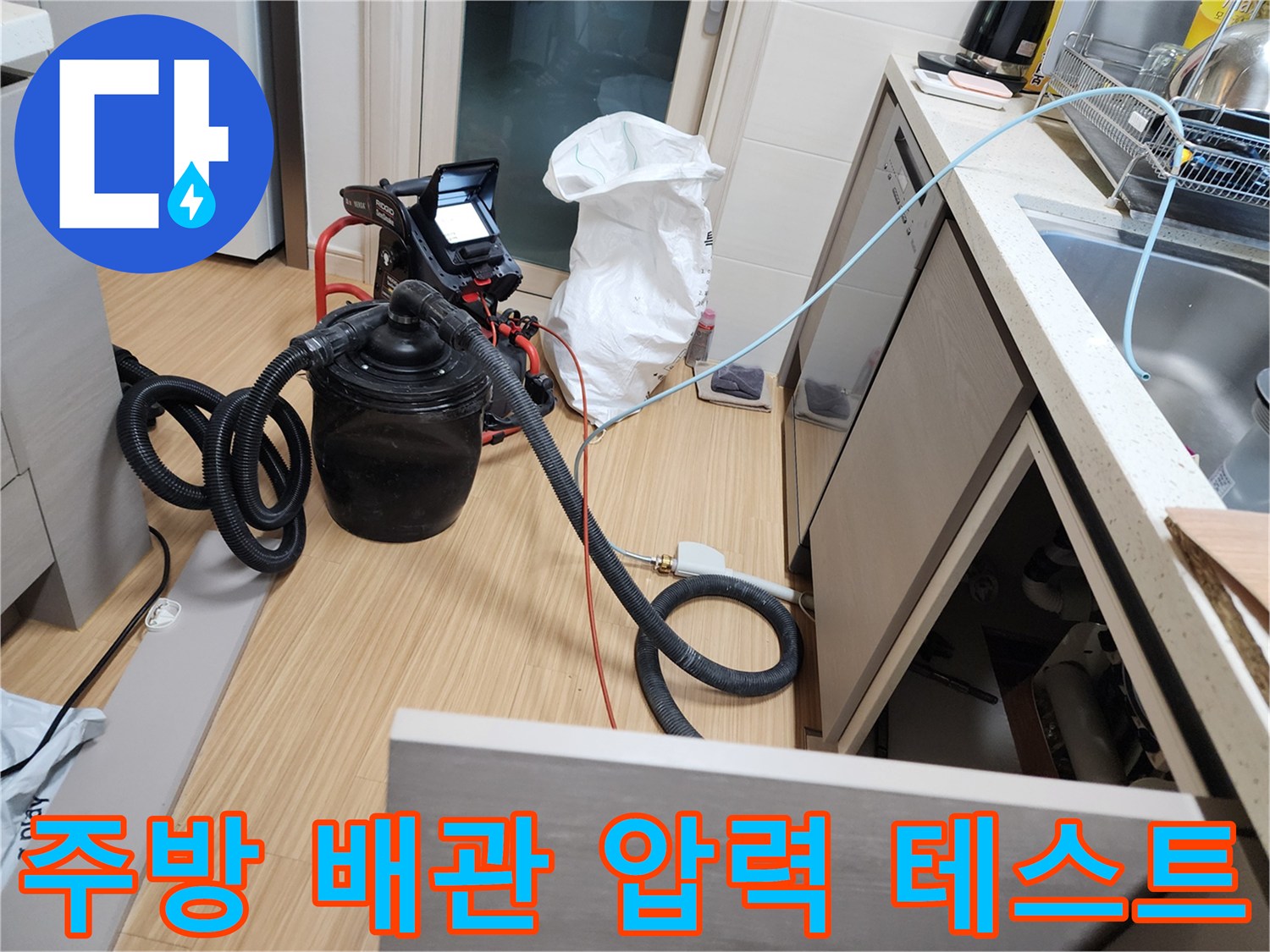 싱크대 하부장 내부에서 진행 중인 배관 공압 테스트 장비 모습