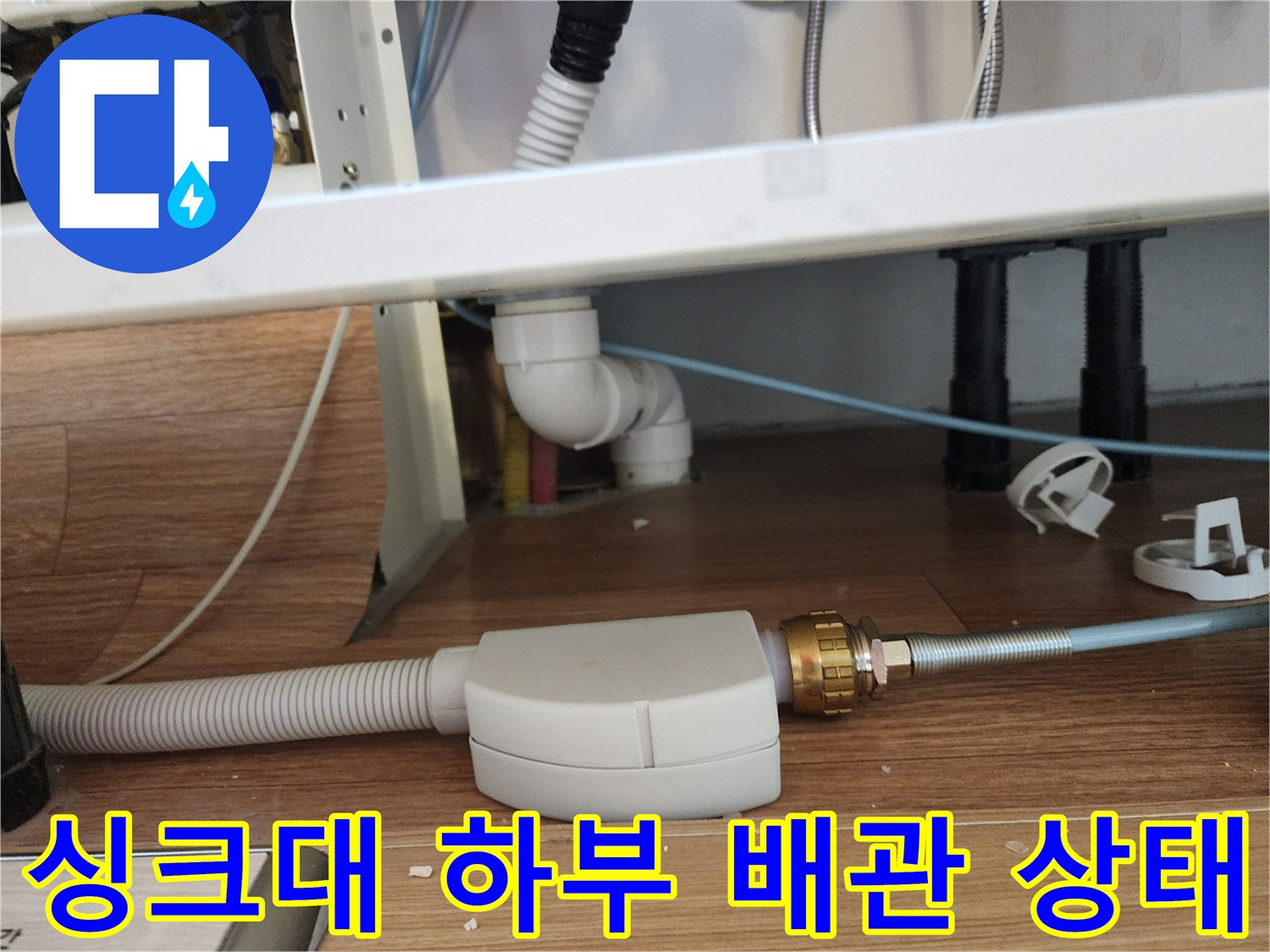 주방 싱크대 아래쪽의 흰색 주름관과 연결 부위 배관 모습