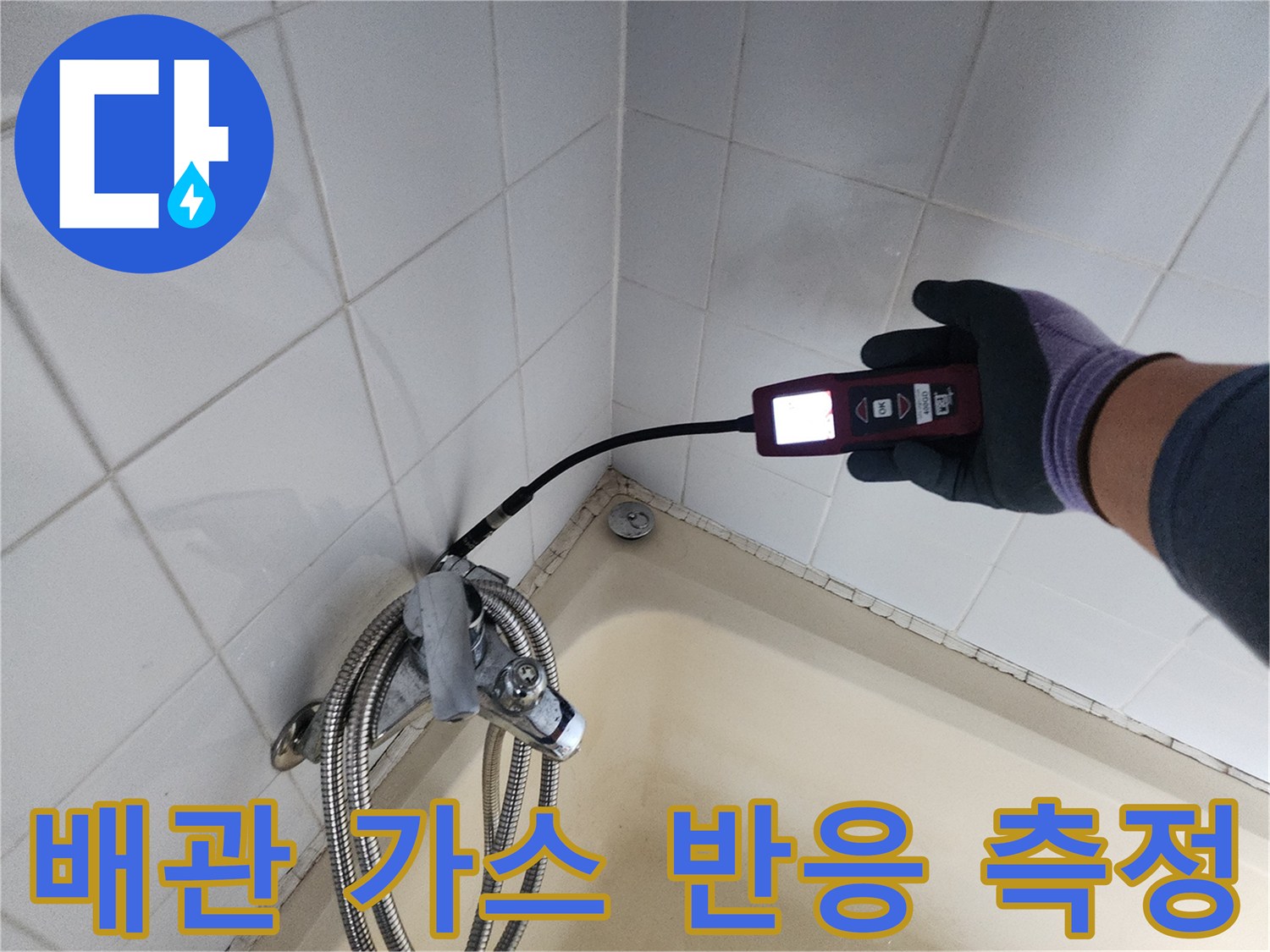 타일 벽면 배관 연결 부위 근처에서 누출 가스를 감지하는 탐지 장비 모습
