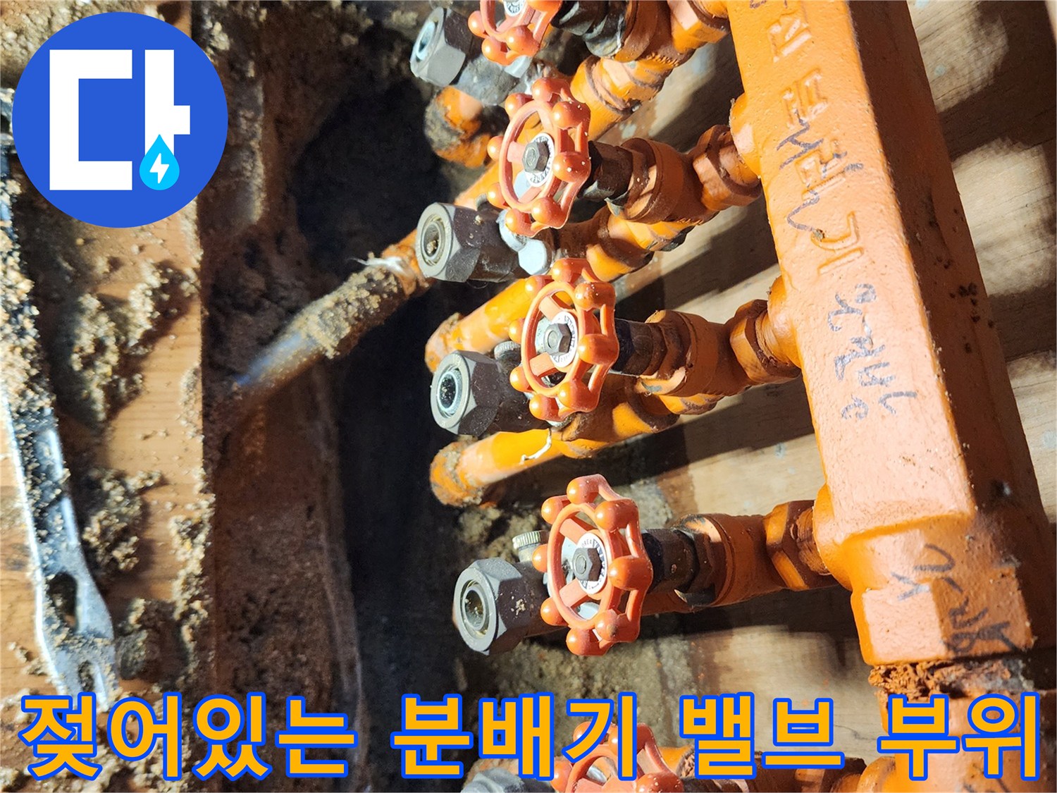 습기로 인해 젖어 있는 오렌지색 배관 보온재와 분배기 밸브 근접 사진