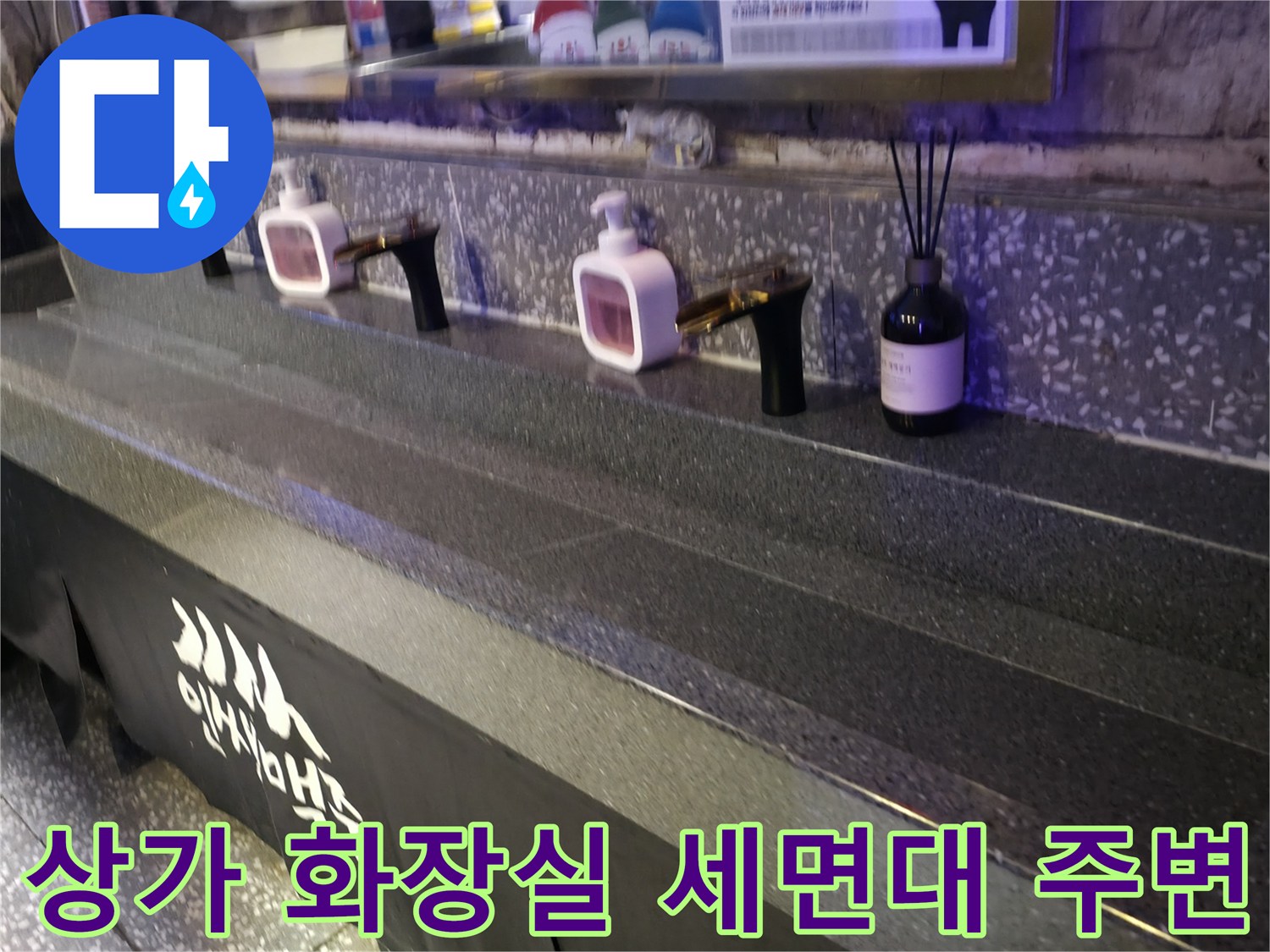 상가 내부 화장실의 검은색 대리석 선반과 수도꼭지 모습