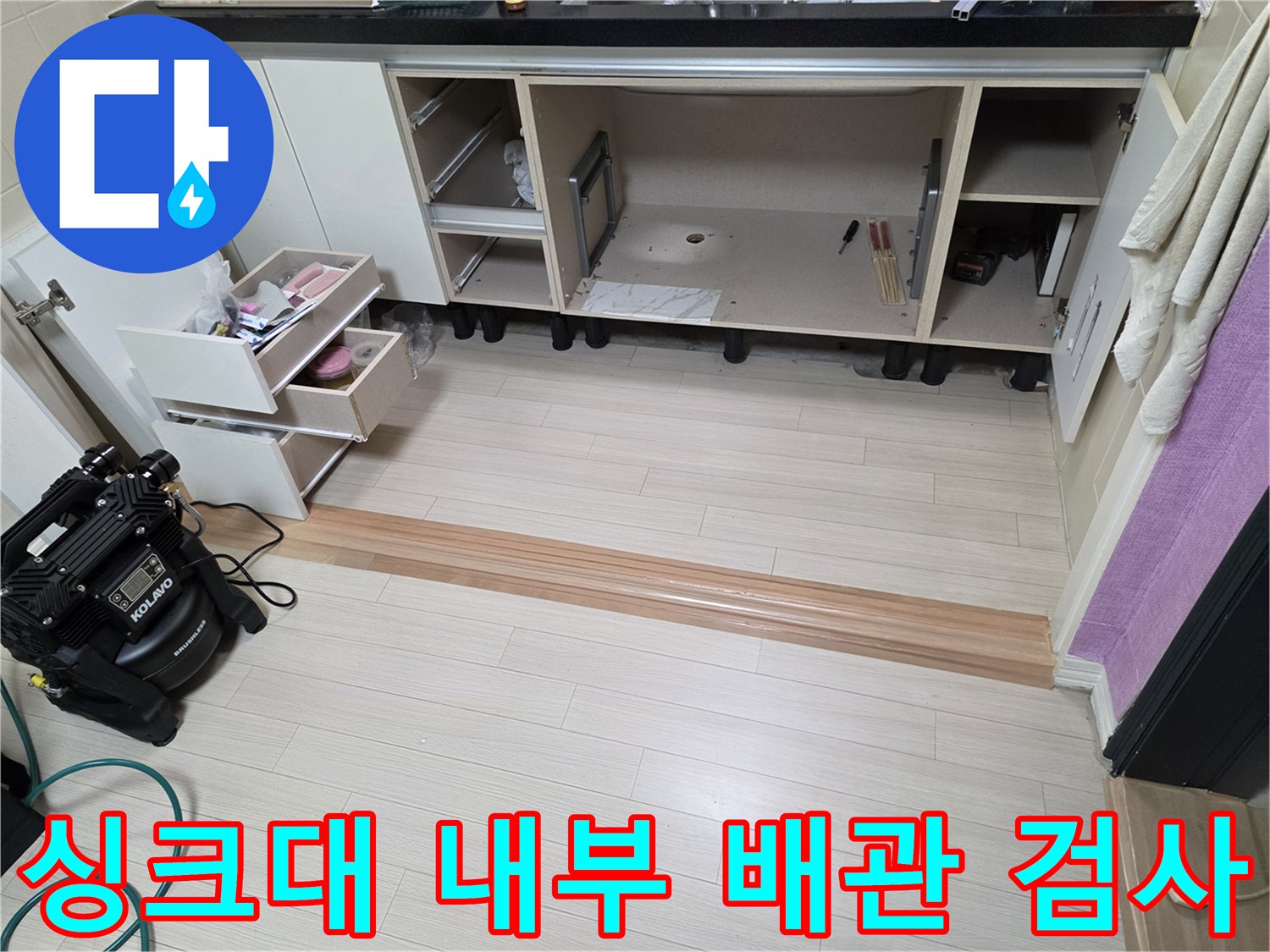 주방 싱크대 하부장 내부의 배관 점검용 장비와 탈거된 서랍들