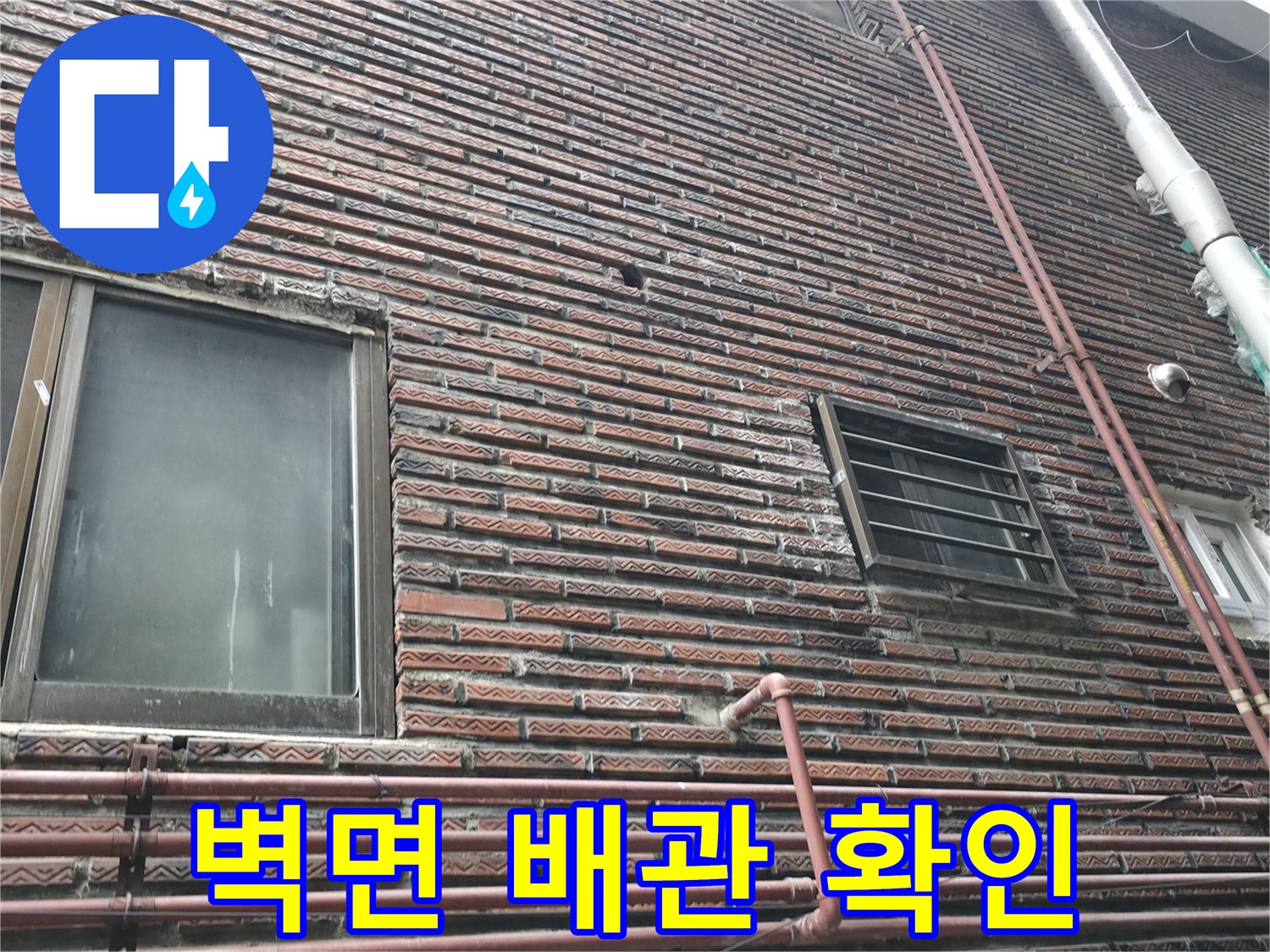 벽돌 외벽과 수직으로 내려오는 외부 배관의 모습