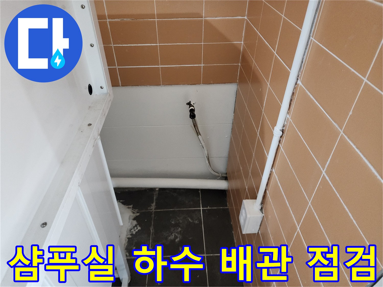 미용실 샴푸대 아래의 배수 배관과 타일 벽면을 촬영한 사진입니다.