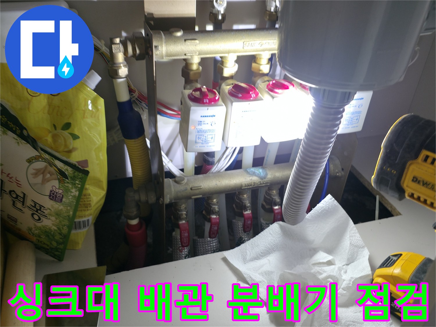싱크대 하부장 내부-배관 분배기와 가스 탐지 장비가 놓여 있는 모습