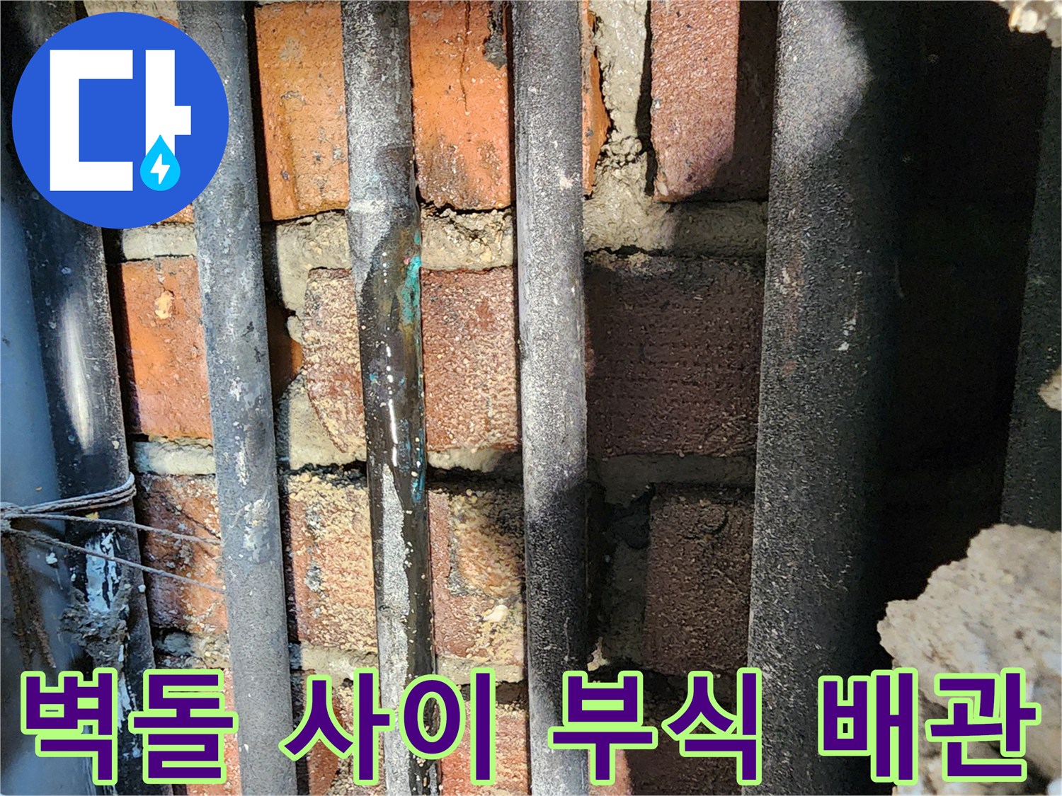붉은 벽돌 구조물 사이에 배치된 노후된 검은 배관