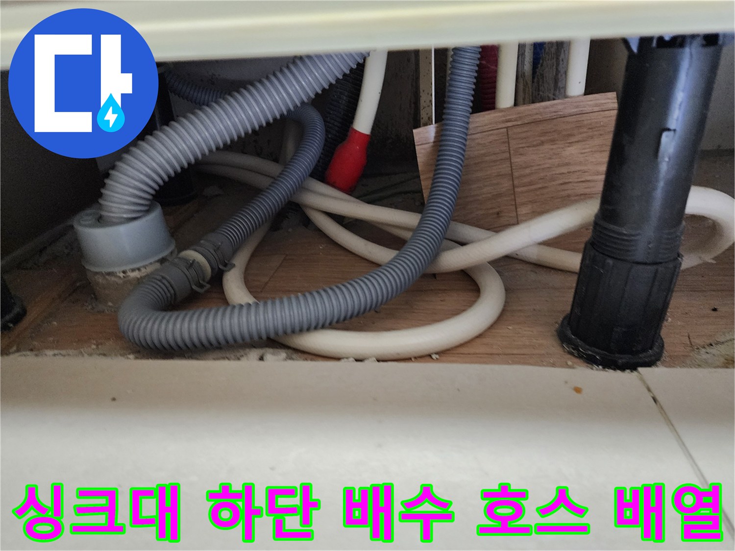 싱크대 밑 공간의 회색 주름관과 흰색 배수 호스의 연결 상태