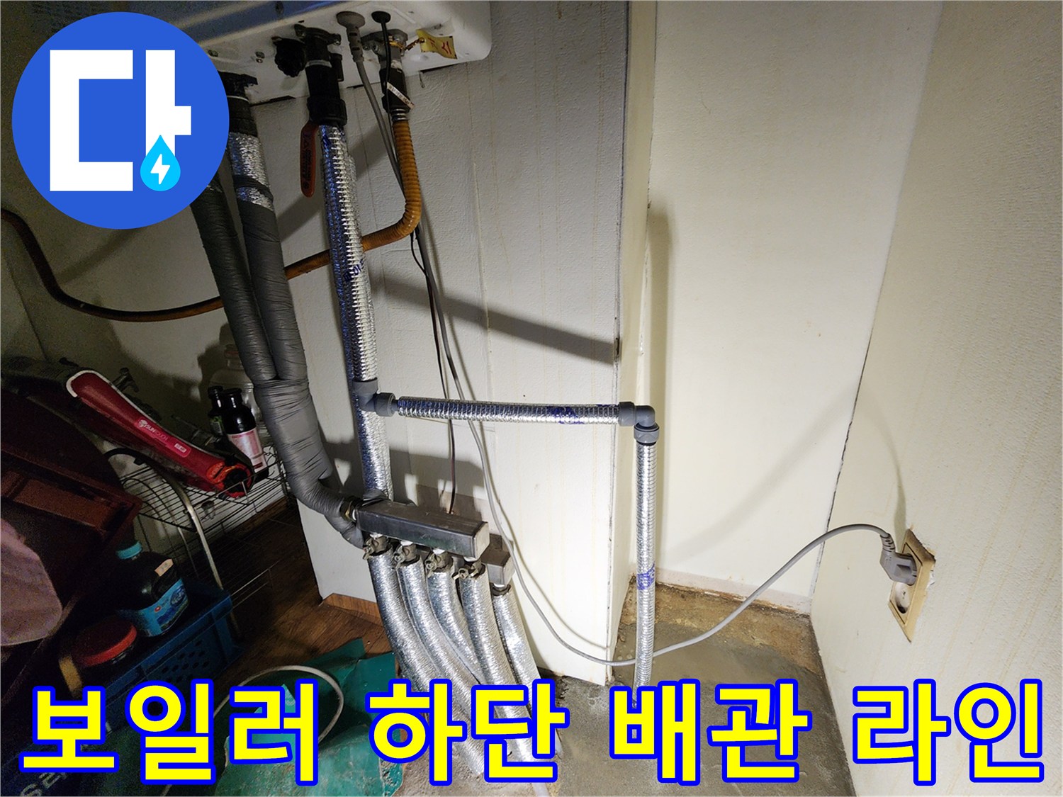은색 보온재가 씌워진 보일러 연결 배관과 벽면 콘센트