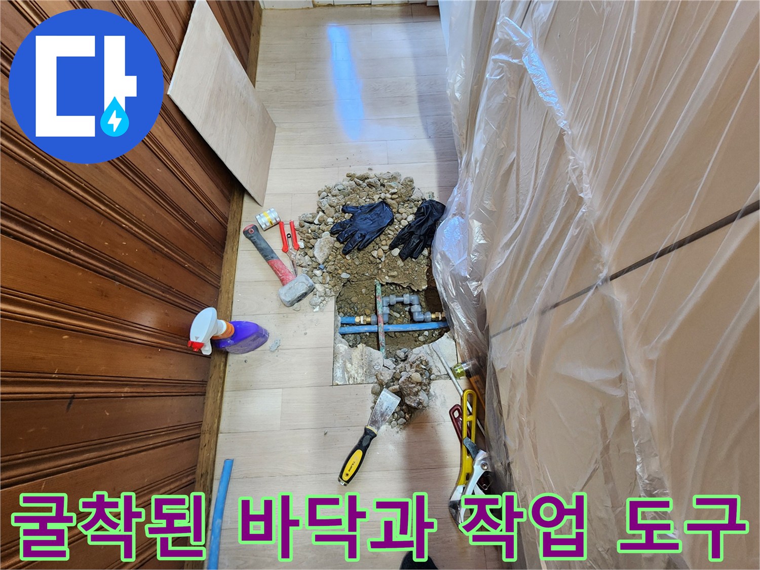 배관 수리를 위해 흙을 파낸 주방 바닥과 작업용 망치 및 장갑