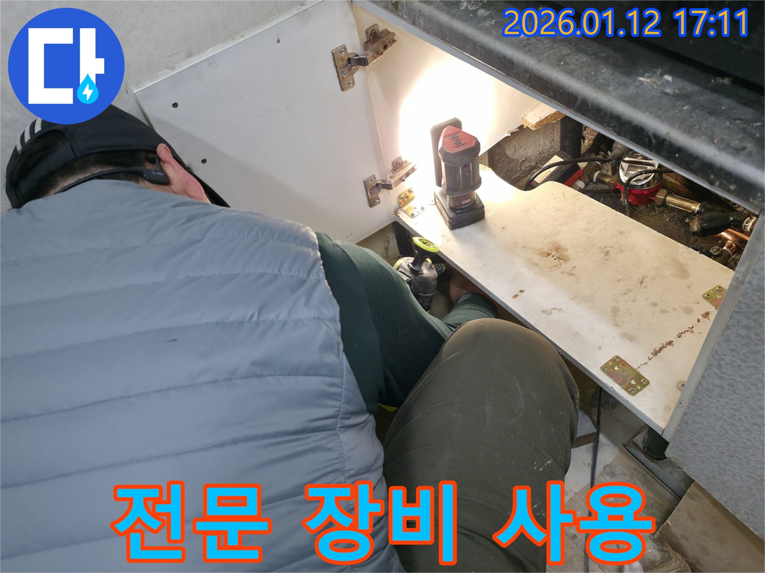 송파구 누수 현장에서 - 누수 전문가가 전문 장비를 사용하여 - 싱크대 하부 누수 지점을 정확하게 탐지하는 모습입니다.