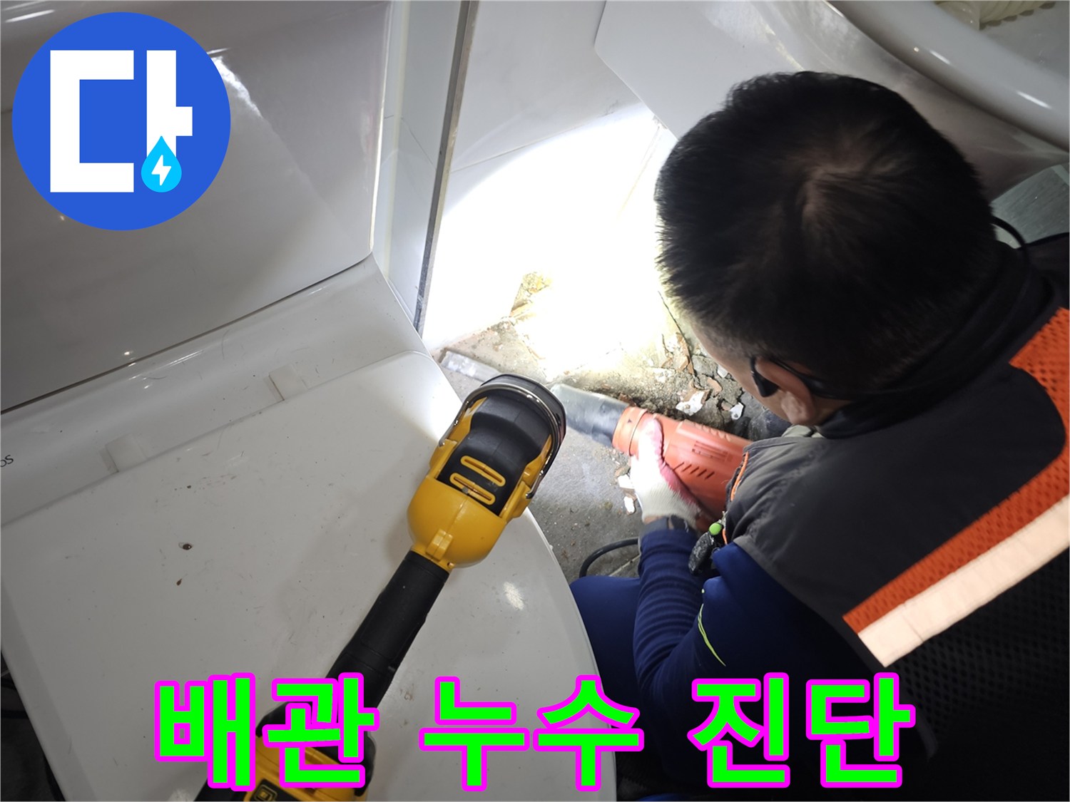 손전등을 이용해 어두운 변기 뒤쪽 배관 틈새를 조사합니다.