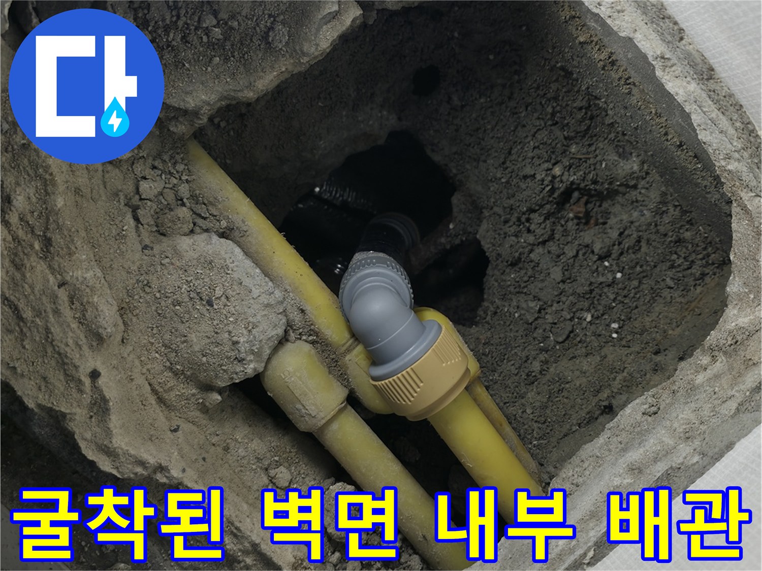 벽을 뚫고 드러난 노란색 매립 배관과 주변 콘크리트 파편